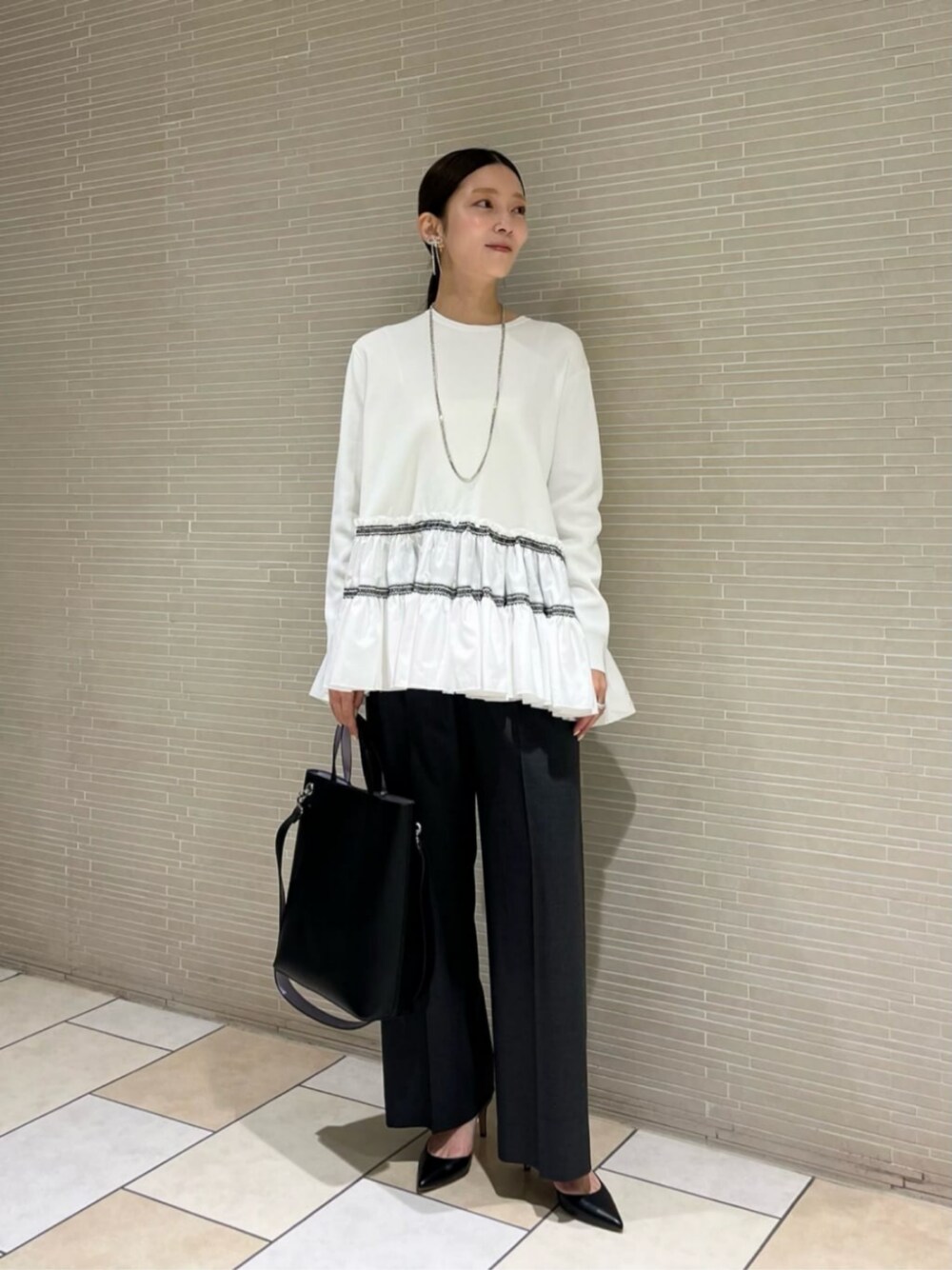 ブラック系のパンプス、グレー系のその他パンツ、ホワイト系のニット/セーターを着用したレディースの冬コーディネートの1枚目の写真