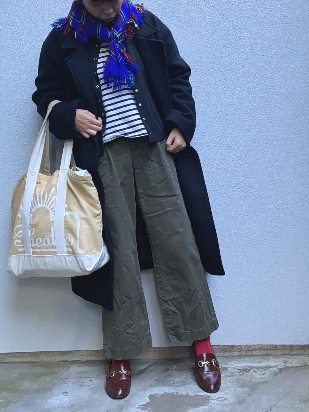 ベージュ系のトートバッグ、グリーン系のチノパンツ、イエロー系のローファーを着用したレディースの冬コーディネートの1枚目の写真