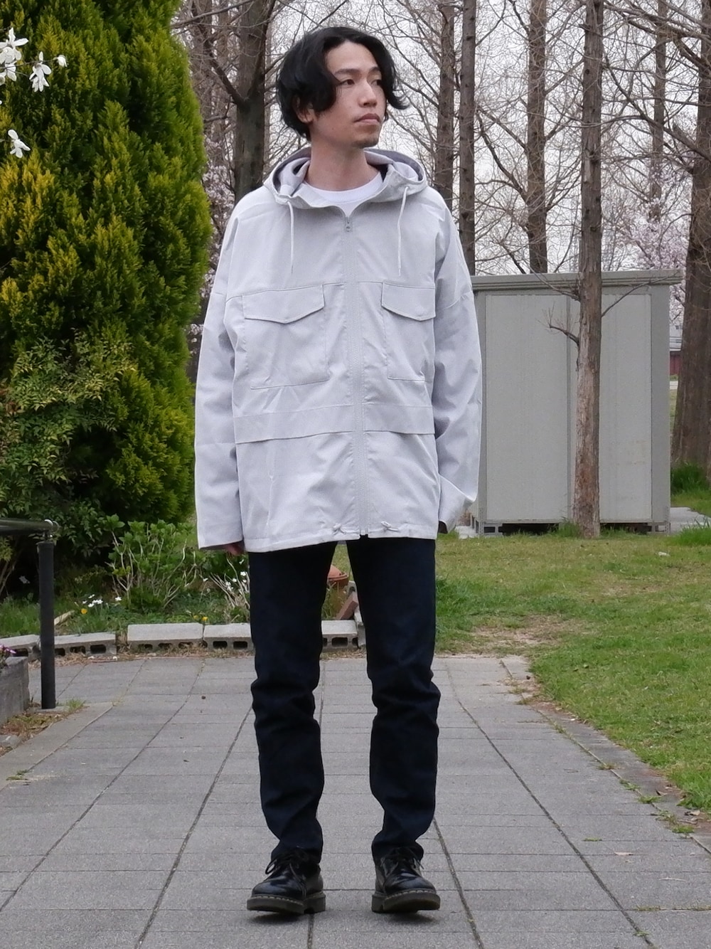 ホワイト系のマウンテンパーカー、ブルー系のデニムパンツ、ブラック系のドレスシューズを着用したメンズの春コーディネートの1枚目の写真