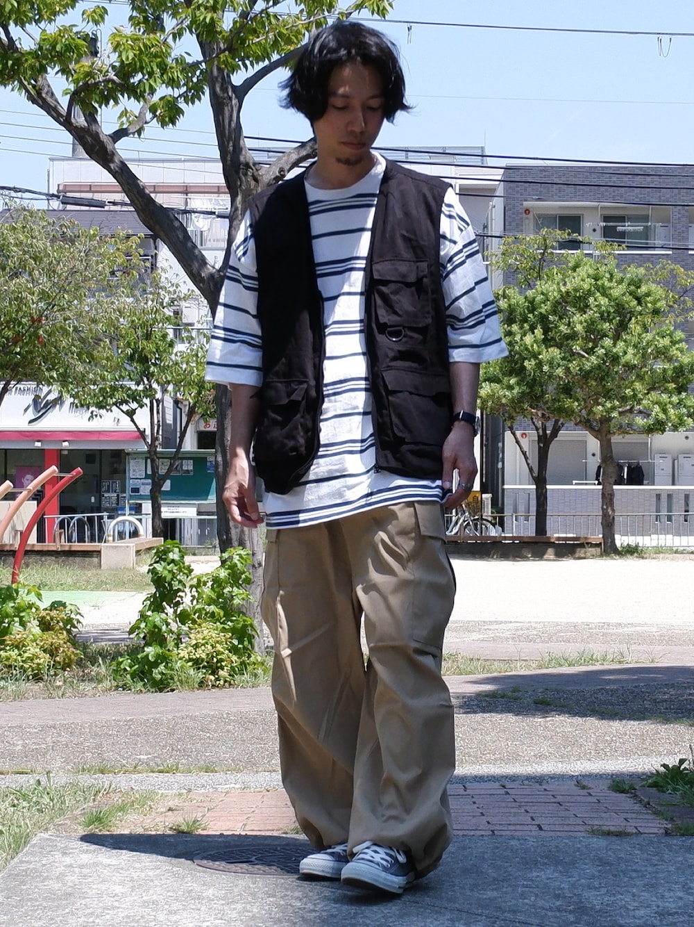 ブラック系のベスト、ホワイト系のTシャツ/カットソー、ベージュ系のカーゴパンツを着用したメンズの夏コーディネートの1枚目の写真