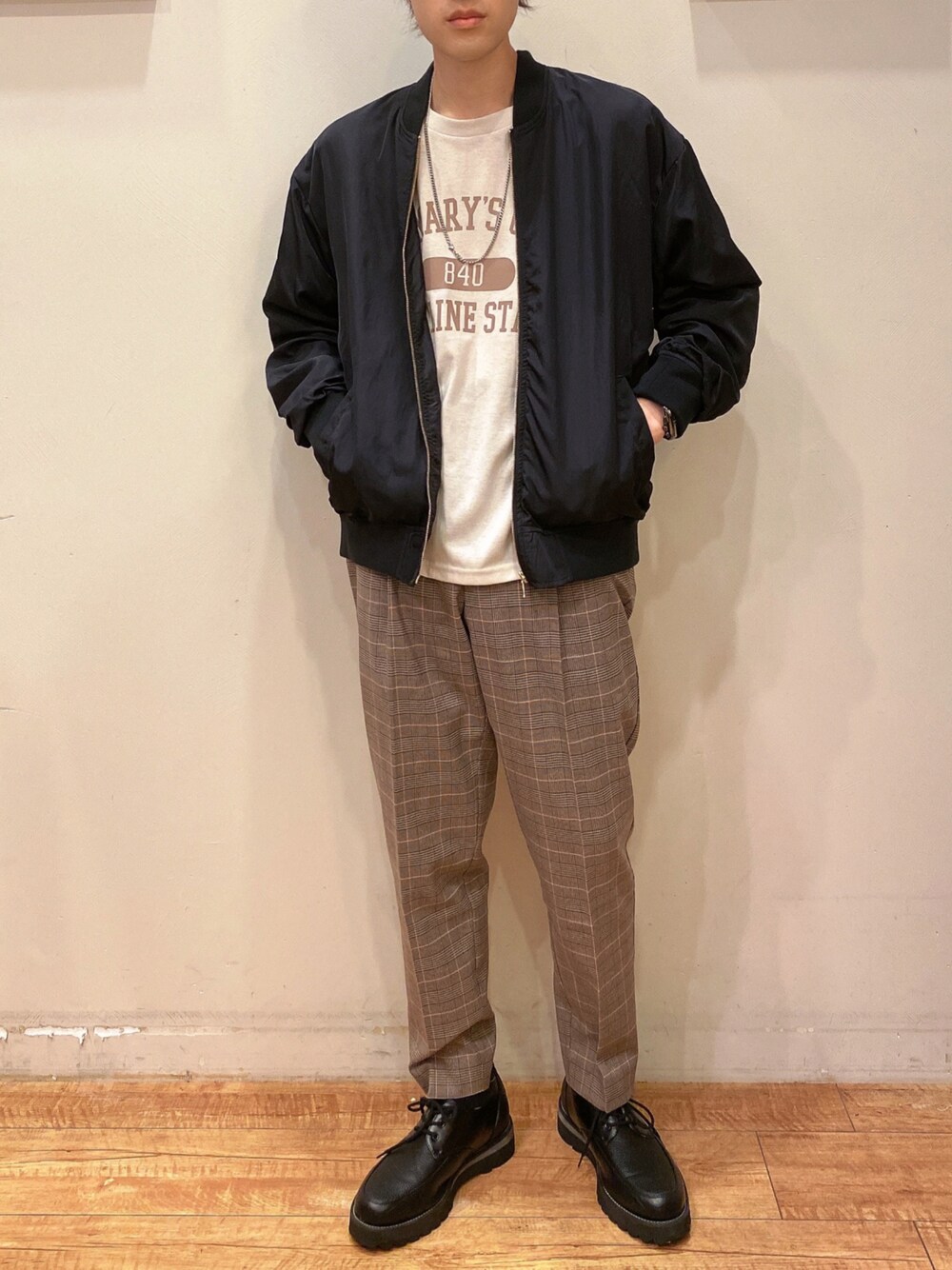 ブラック系のドレスシューズ、ブラック系のブルゾン、ベージュ系のTシャツ/カットソーを着用したメンズの秋コーディネートの1枚目の写真