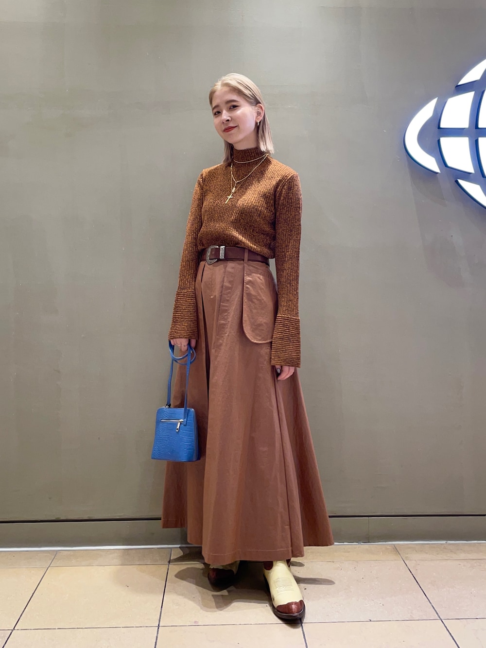 ブラウン系のスカート、オレンジ系のニット/セーターを着用したレディースの秋コーディネートの1枚目の写真