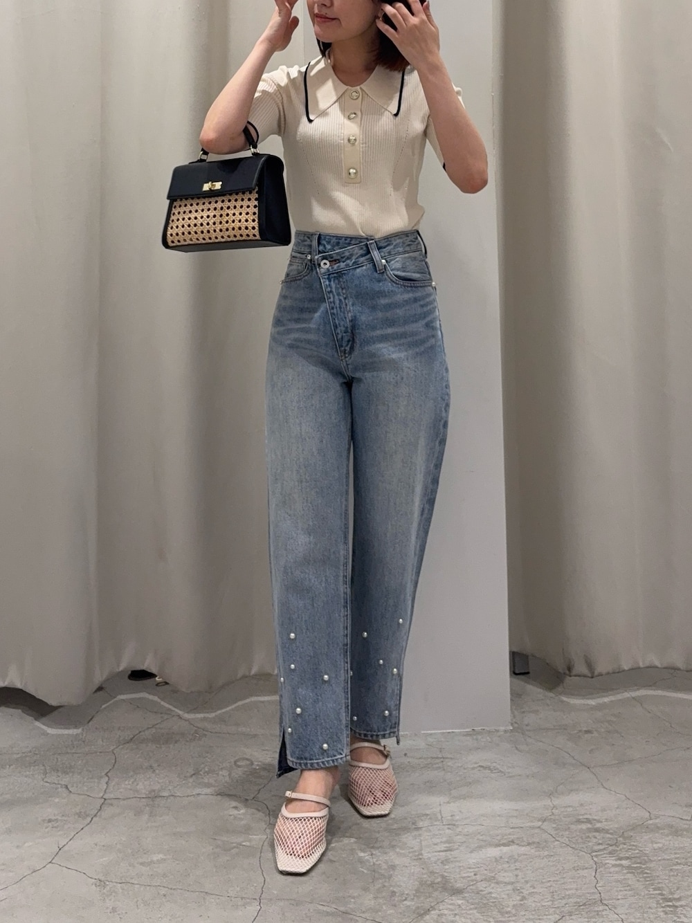 ブルー系のデニムパンツ、ブラック系のハンドバッグ、ホワイト系のニット/セーターを着用したレディースの春コーディネートの1枚目の写真