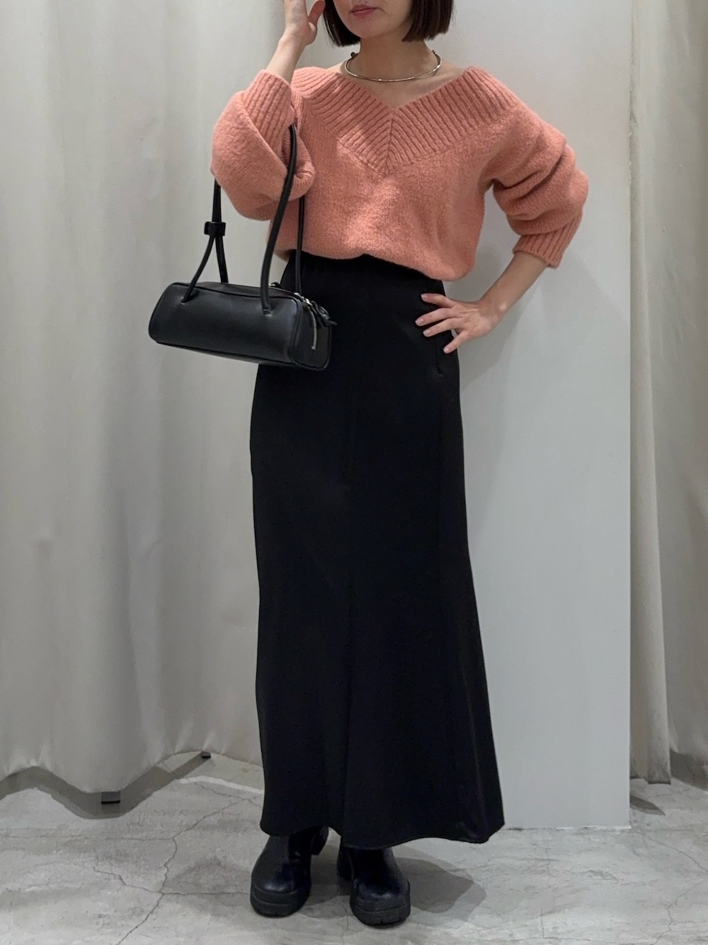 ブラック系のスカート、ピンク系のニット/セーター、ブラック系のショルダーバッグを着用したレディースの冬コーディネートの1枚目の写真