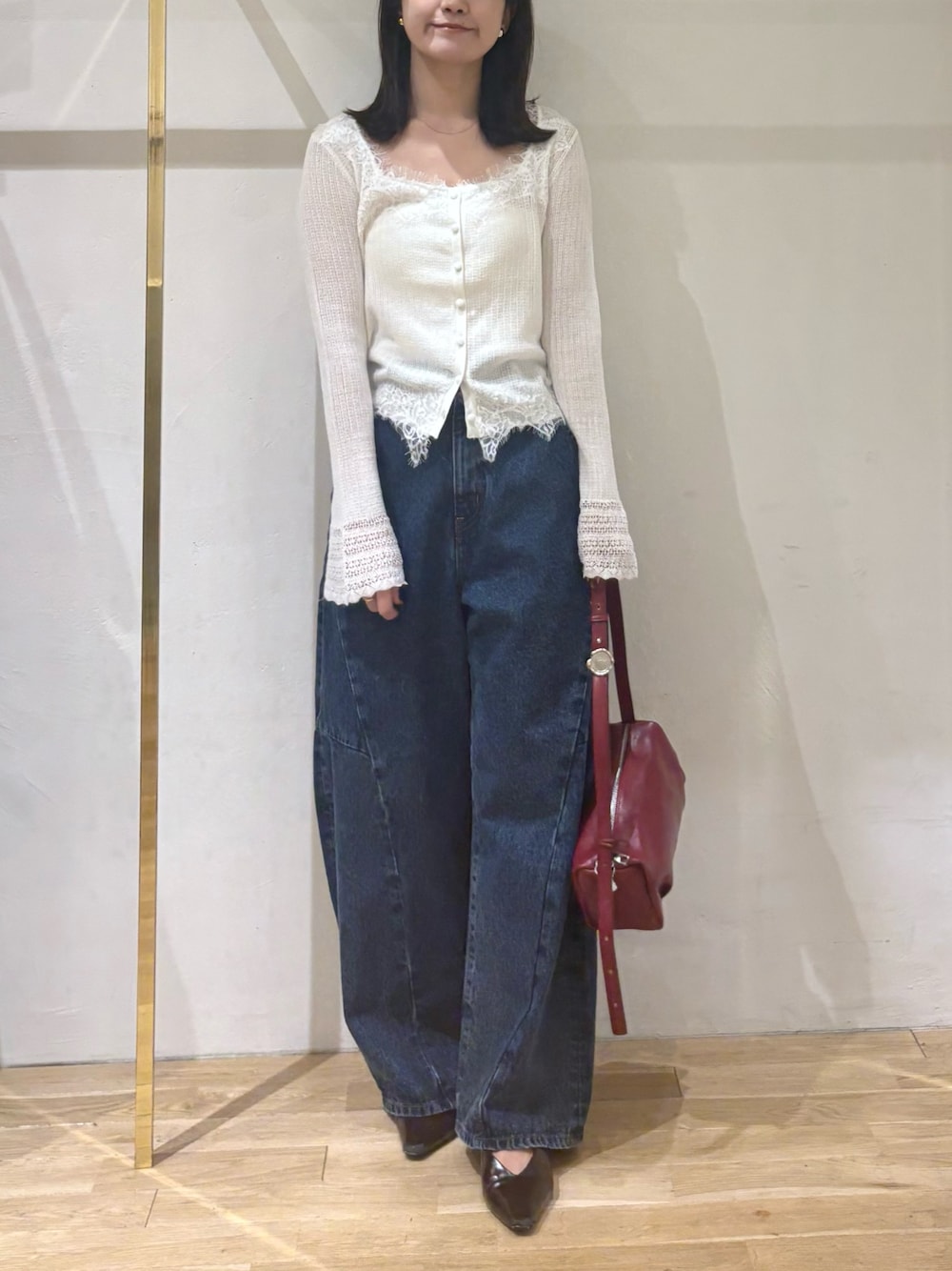 ホワイト系のカーディガン/ボレロ、ブルー系のデニムパンツ、レッド系のハンドバッグを着用したレディースの秋コーディネートの1枚目の写真