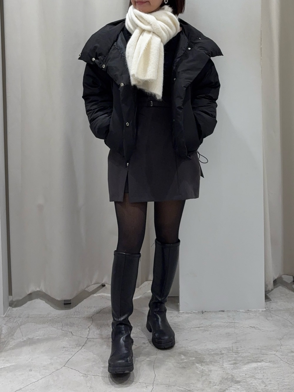 ブラック系のダウンジャケット/コート、グレー系のスカート、ブラック系のニット/セーターを着用したレディースの冬コーディネートの1枚目の写真