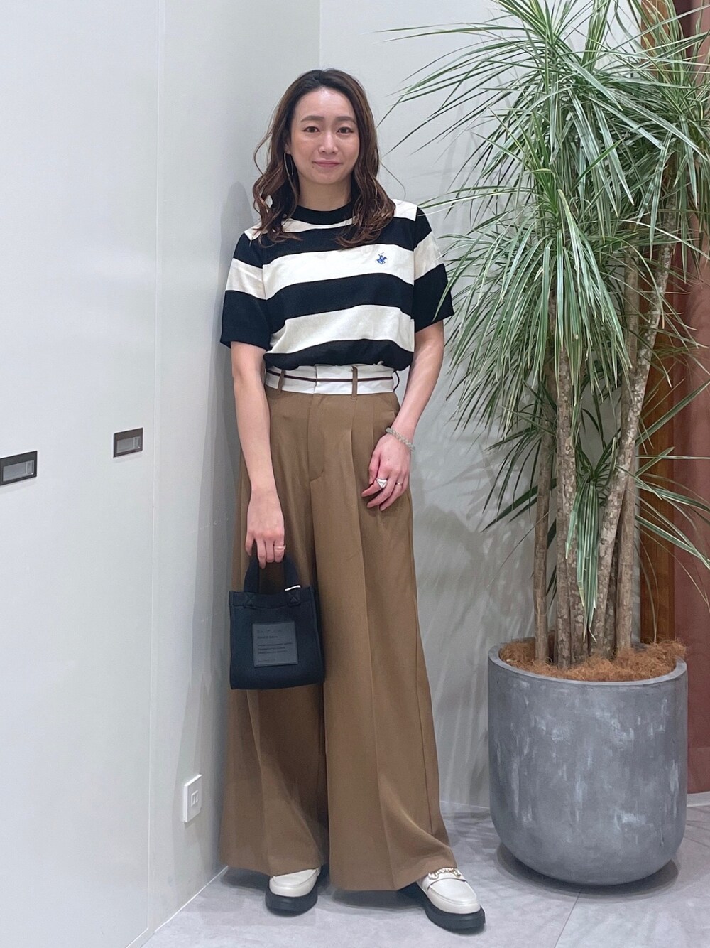 ブラック系のニット/セーター、ベージュ系のその他パンツ、ブラック系のショルダーバッグを着用したレディースの春コーディネートの1枚目の写真