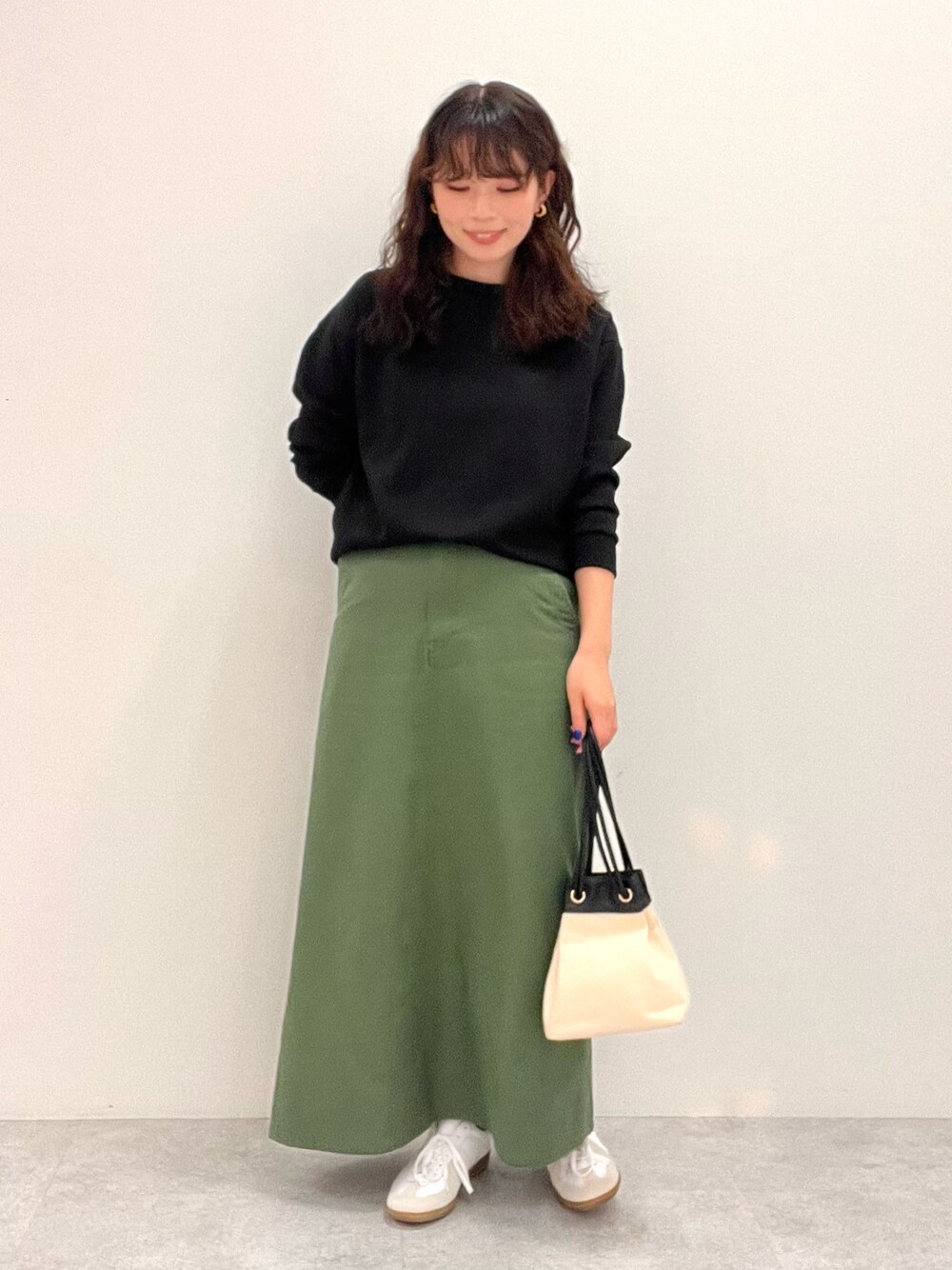 ブラック系のスウェット、グリーン系のスカートを着用したレディースの冬コーディネートの1枚目の写真