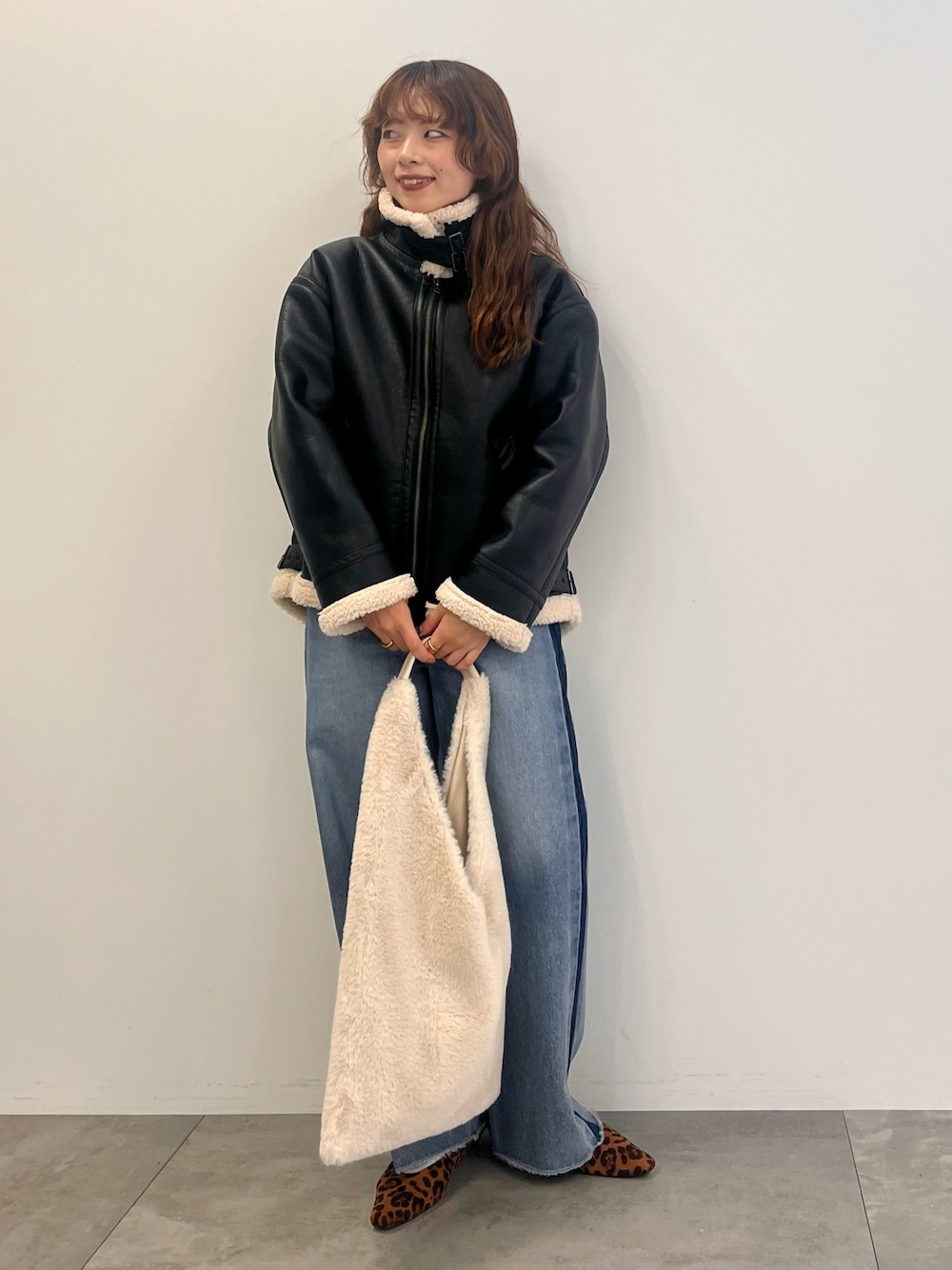 ブルー系のデニムパンツ、ブラック系のその他アウター、ベージュ系のショルダーバッグを着用したレディースの秋コーディネートの1枚目の写真