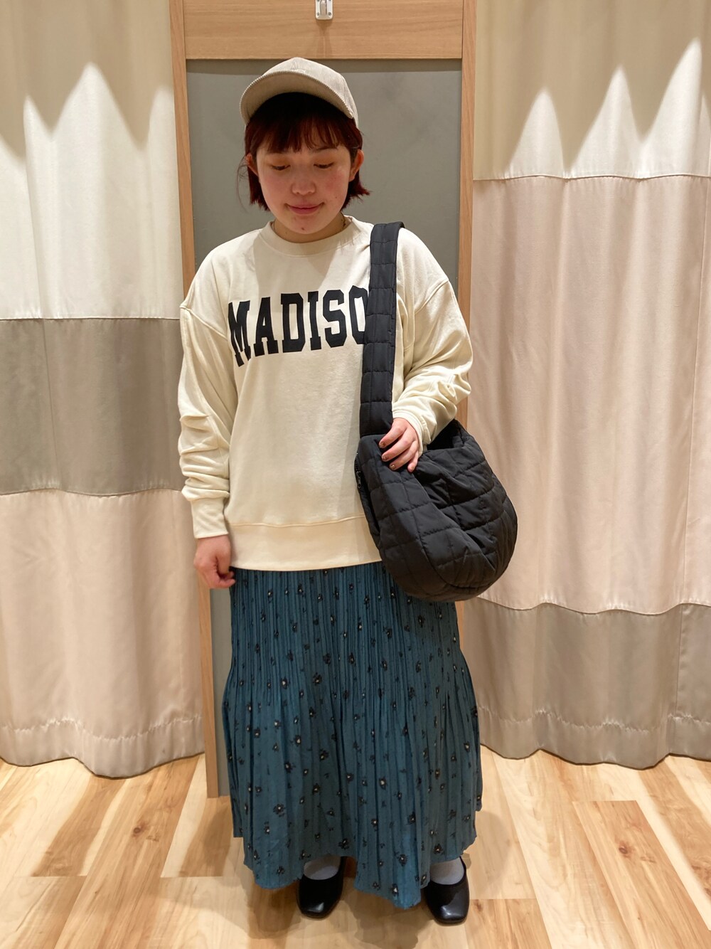 ブラック系のハンドバッグ、ホワイト系のTシャツ/カットソー、グリーン系のスカートを着用したレディースの秋コーディネートの1枚目の写真