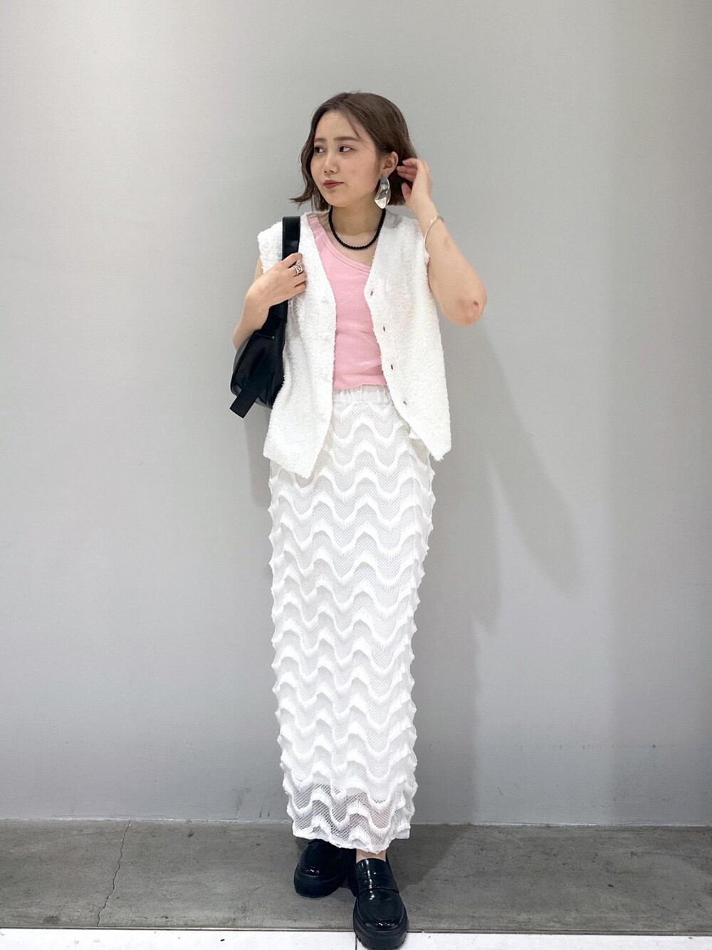 ブラック系のローファー、ブラック系のショルダーバッグ、ホワイト系のベストを着用したレディースの春コーディネートの1枚目の写真