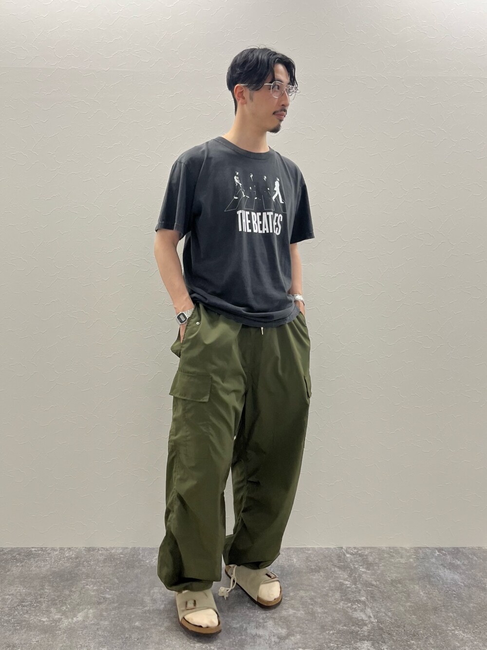 ブラック系のTシャツ/カットソー、グリーン系のカーゴパンツを着用したメンズの春コーディネートの1枚目の写真