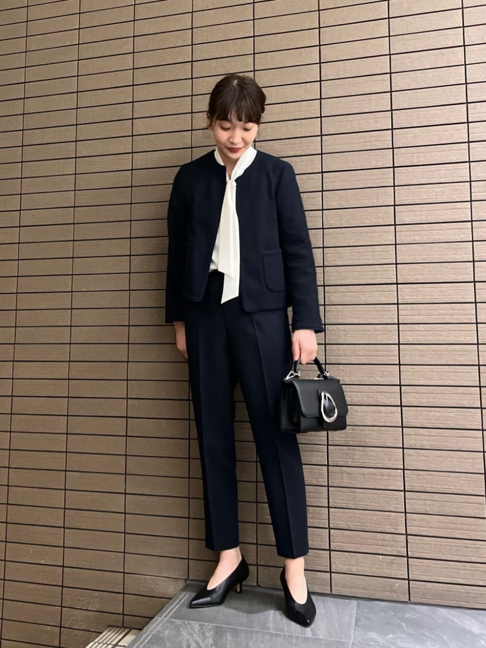 ブラック系のパンプス、ブルー系のノーカラージャケット、ホワイト系のシャツ/ブラウスを着用したレディースの春コーディネートの1枚目の写真