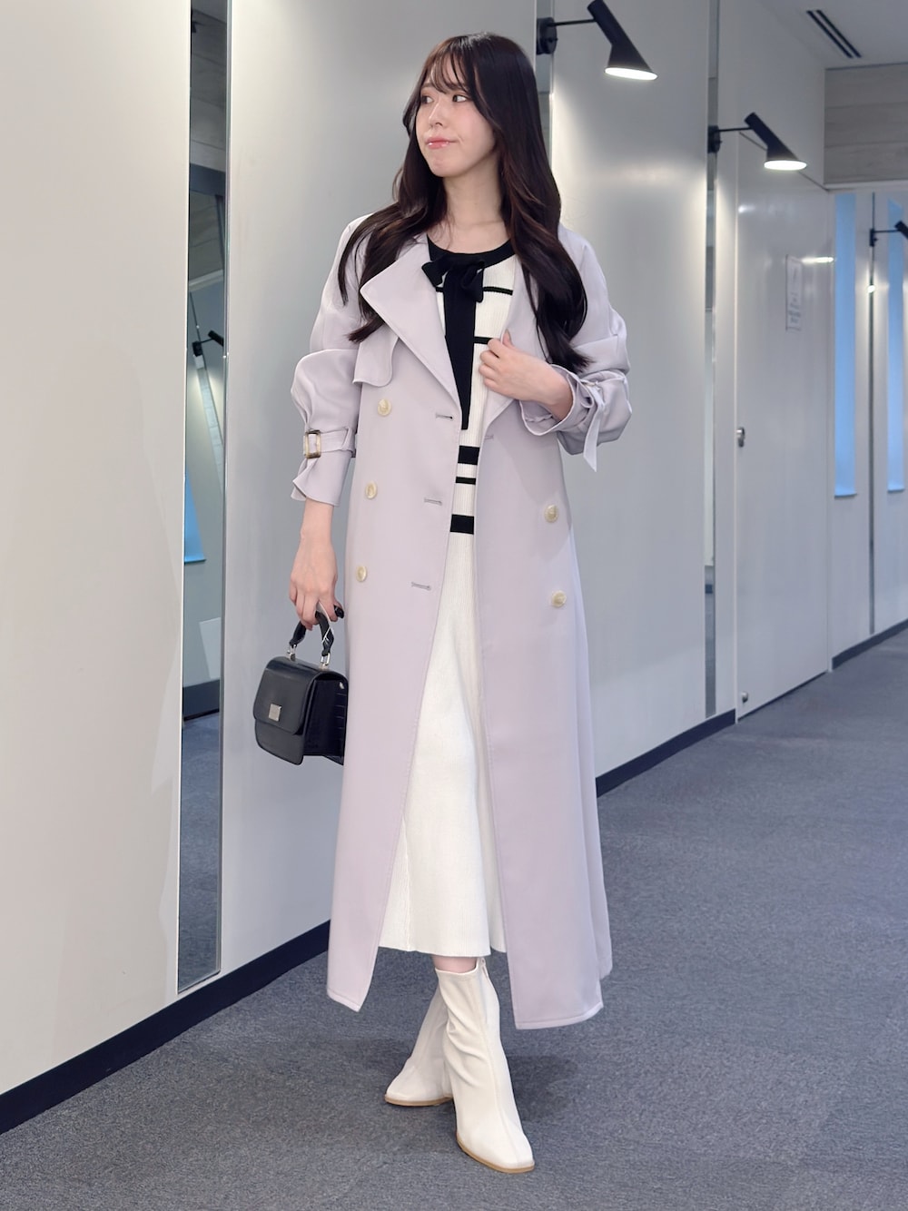 パープル系のトレンチコート、ホワイト系のワンピース、ブラック系のハンドバッグを着用したレディースの冬コーディネートの1枚目の写真