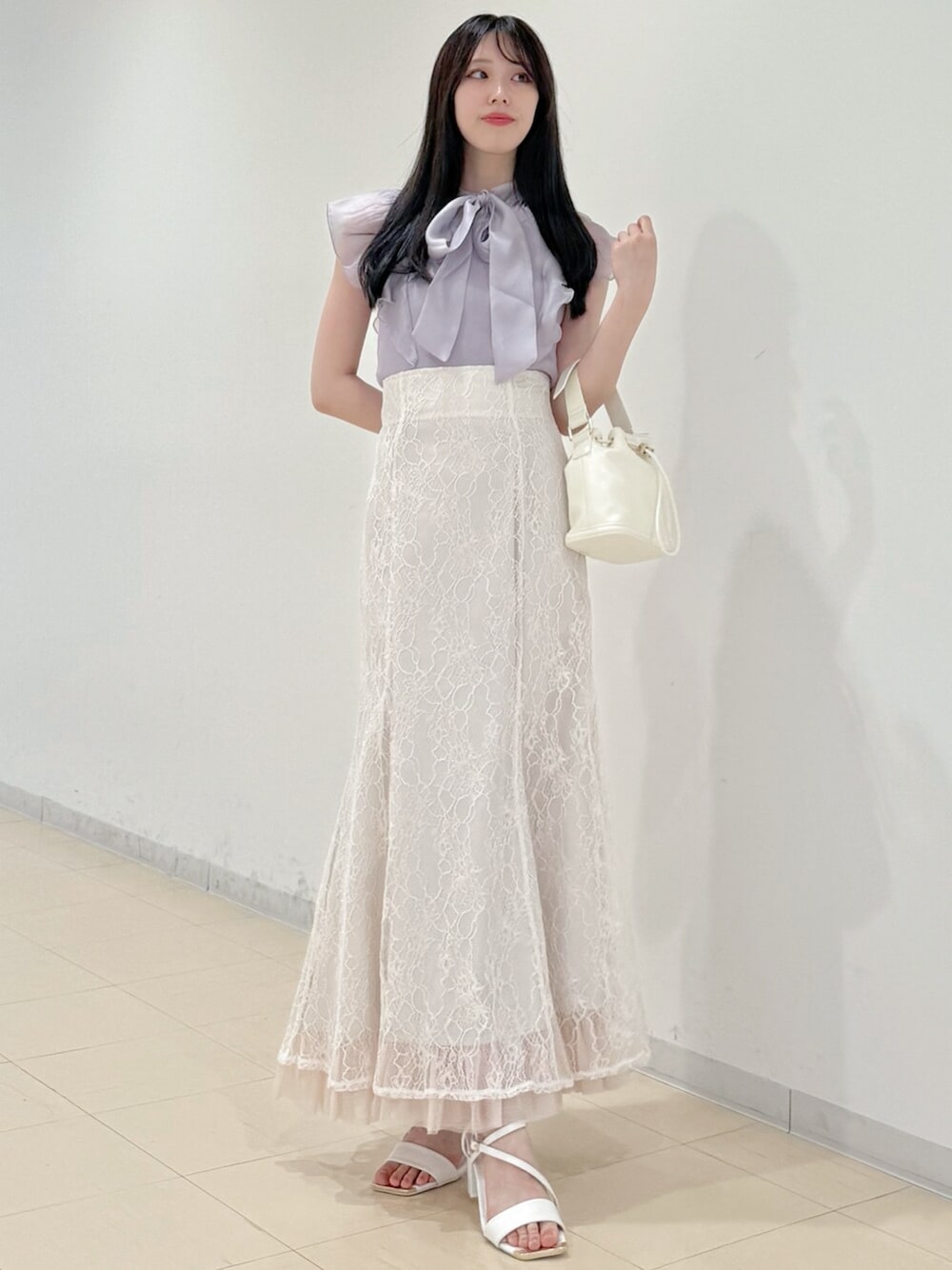 ホワイト系のスカート、ホワイト系のサンダル、ホワイト系のハンドバッグを着用したレディースの春コーディネートの1枚目の写真