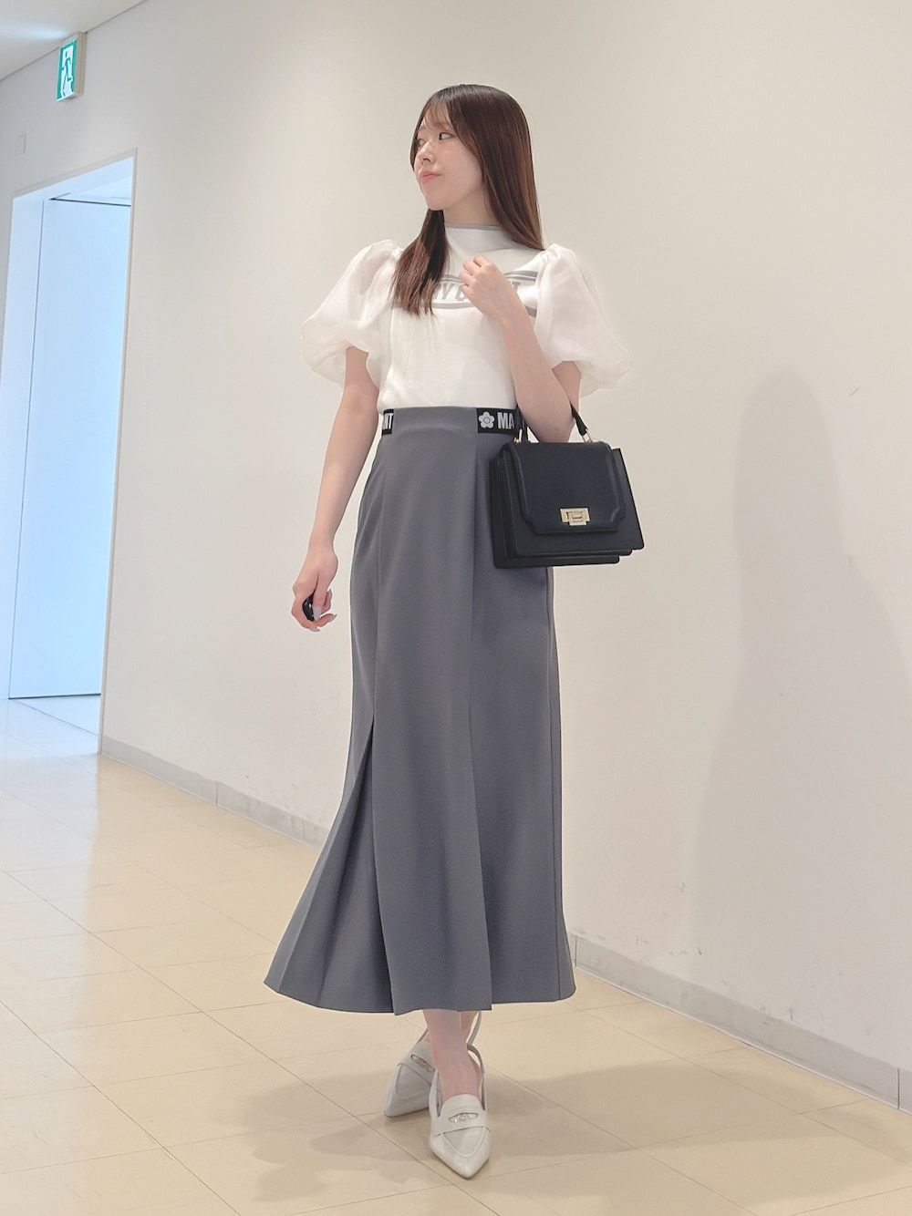 ホワイト系のニット/セーター、グレー系のスカート、ブラック系のハンドバッグを着用したレディースの春コーディネートの1枚目の写真