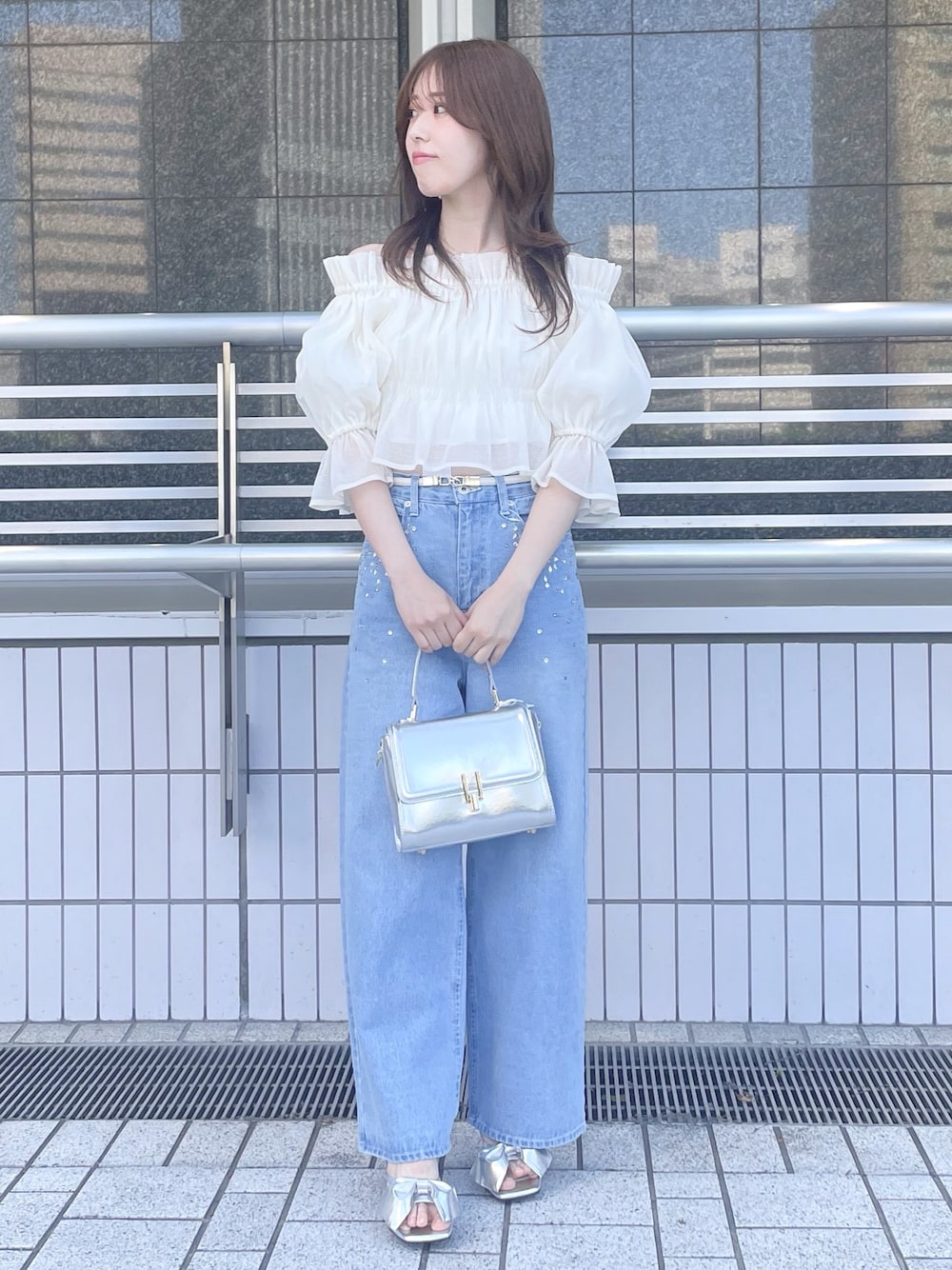 ブルー系のデニムパンツ、シルバー系のハンドバッグ、シルバー系のサンダルを着用したレディースの春コーディネートの1枚目の写真