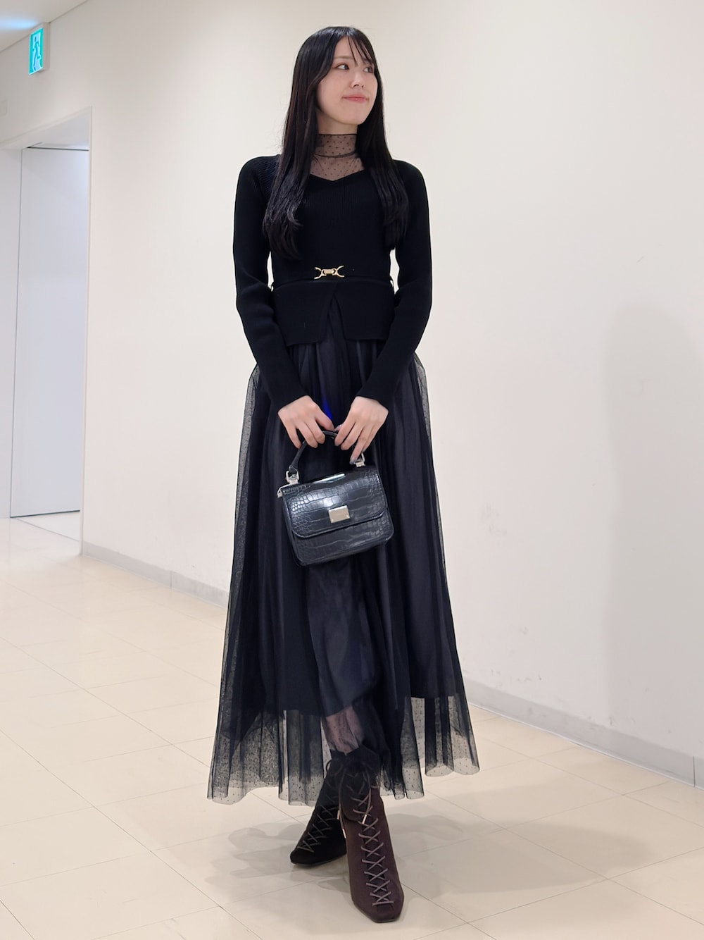 ブラック系のワンピース、ブラック系のハンドバッグ、ブラウン系のブーツを着用したレディースの秋コーディネートの1枚目の写真