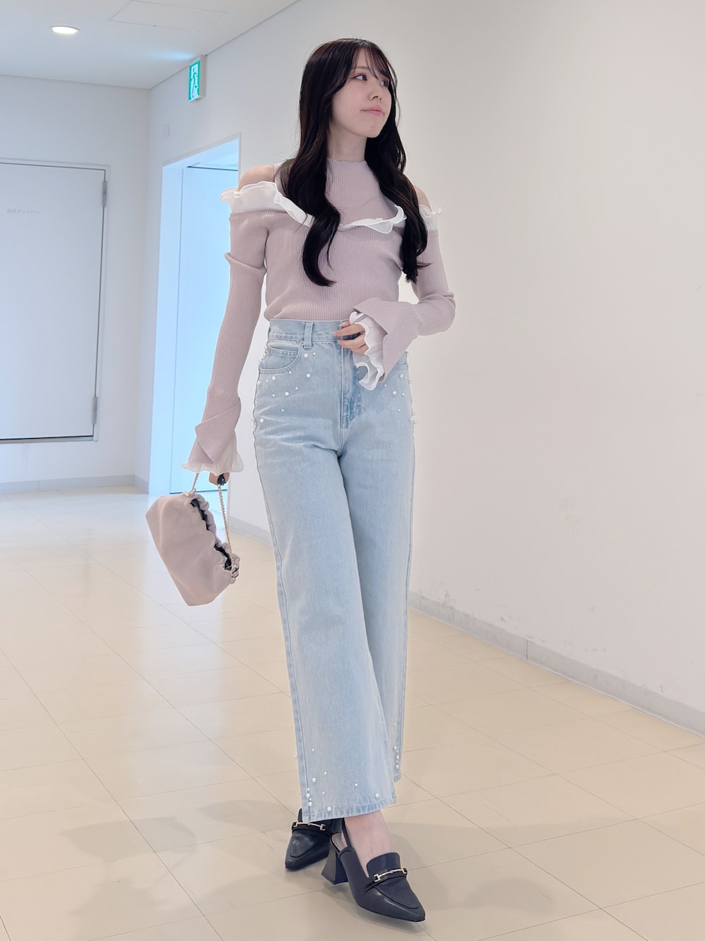ベージュ系のニット/セーター、ブルー系のデニムパンツ、ピンク系のショルダーバッグを着用したレディースの春コーディネートの1枚目の写真