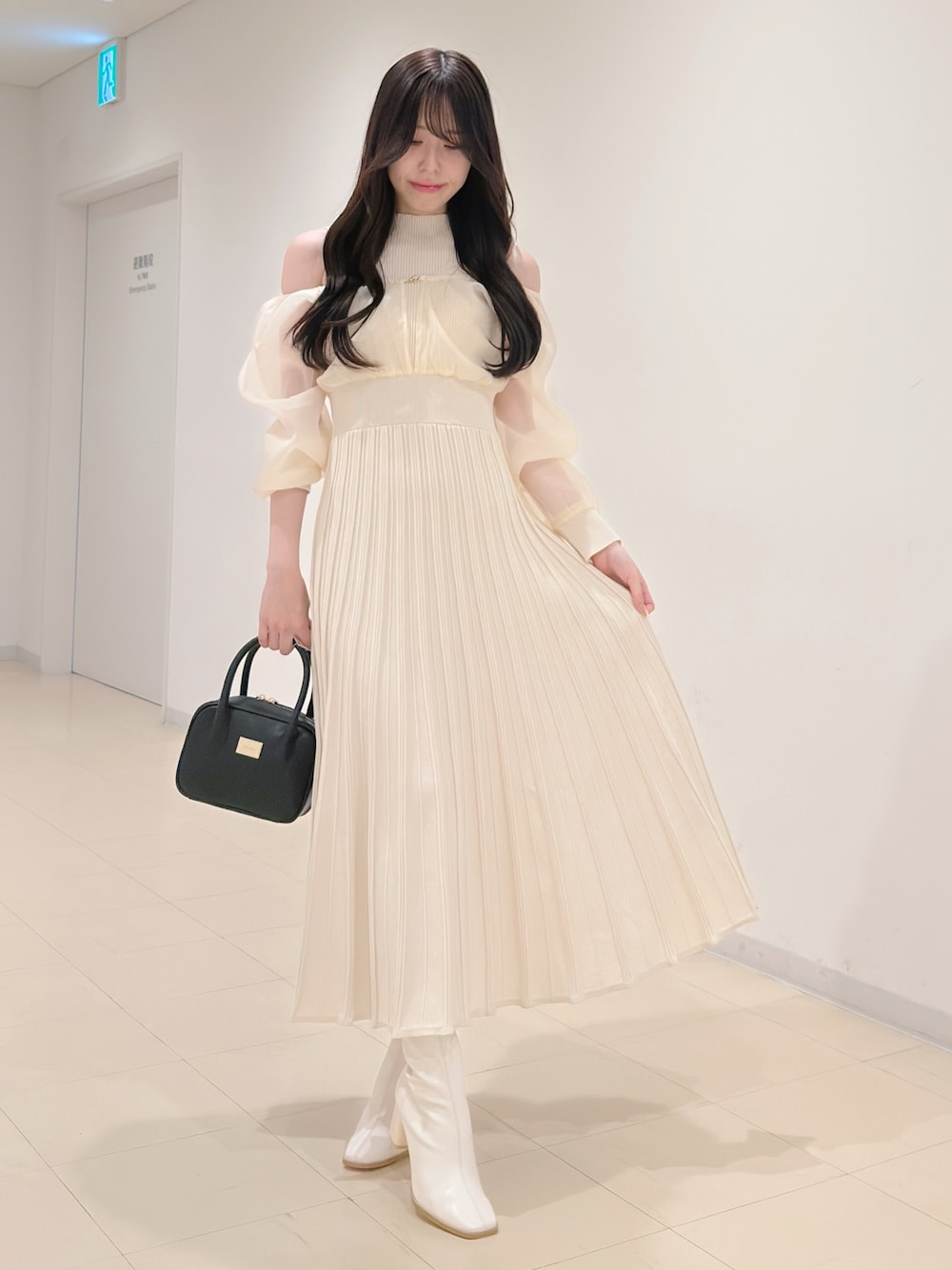 ホワイト系のワンピース、ブラック系のハンドバッグ、ホワイト系のブーツを着用したレディースの冬コーディネートの1枚目の写真