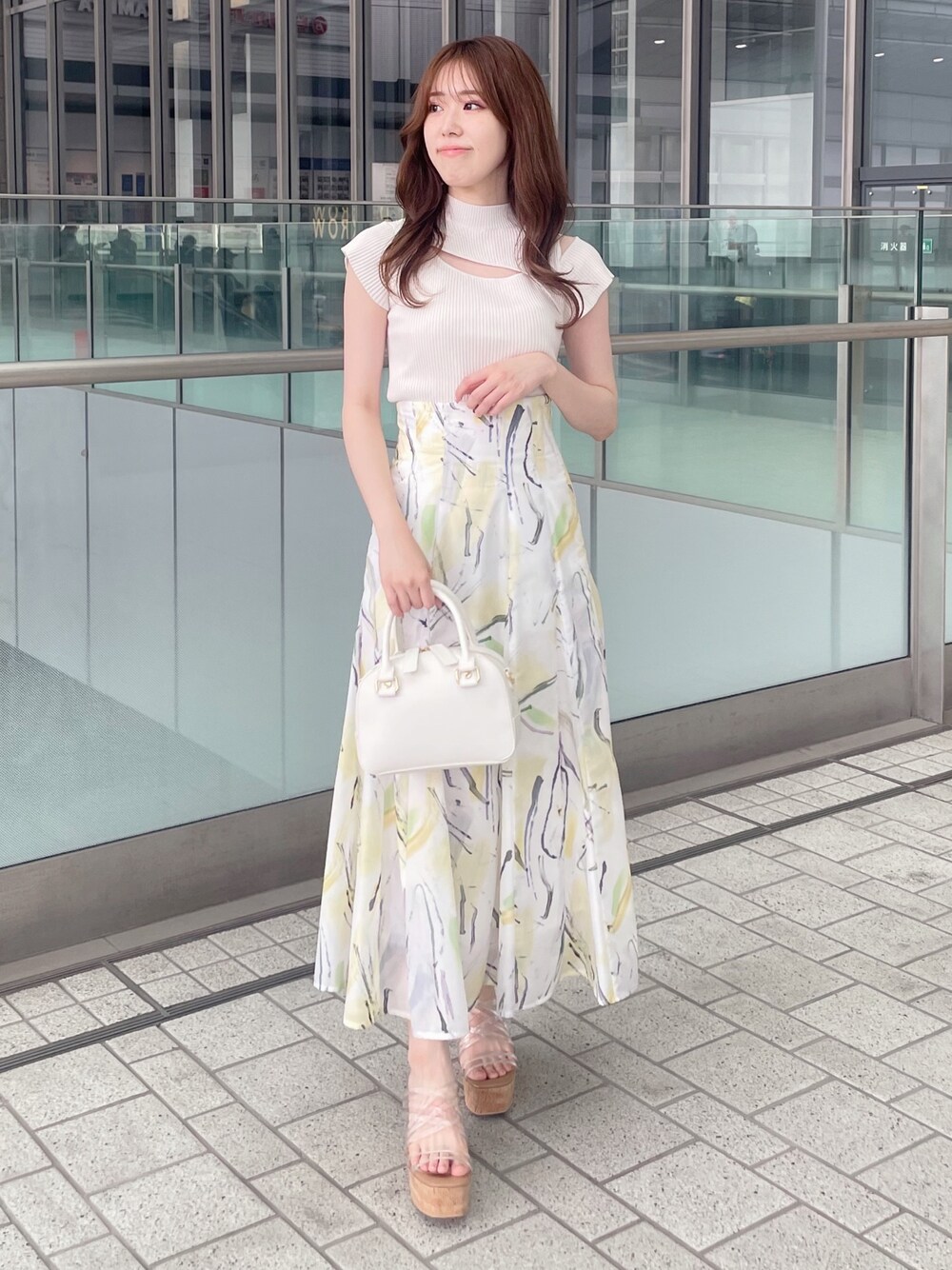 ホワイト系のニット/セーター、イエロー系のスカート、ホワイト系のボストンバッグを着用したレディースの夏コーディネートの1枚目の写真