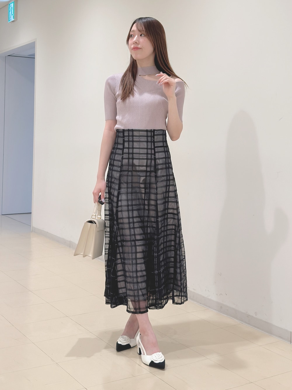 ベージュ系のニット/セーター、ブルー系のスカート、ホワイト系のハンドバッグを着用したレディースの春コーディネートの1枚目の写真