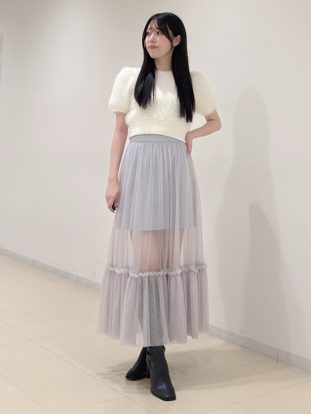 ホワイト系のニット/セーター、ブルー系のスカート、ブラック系のブーツを着用したレディースの夏コーディネートの1枚目の写真