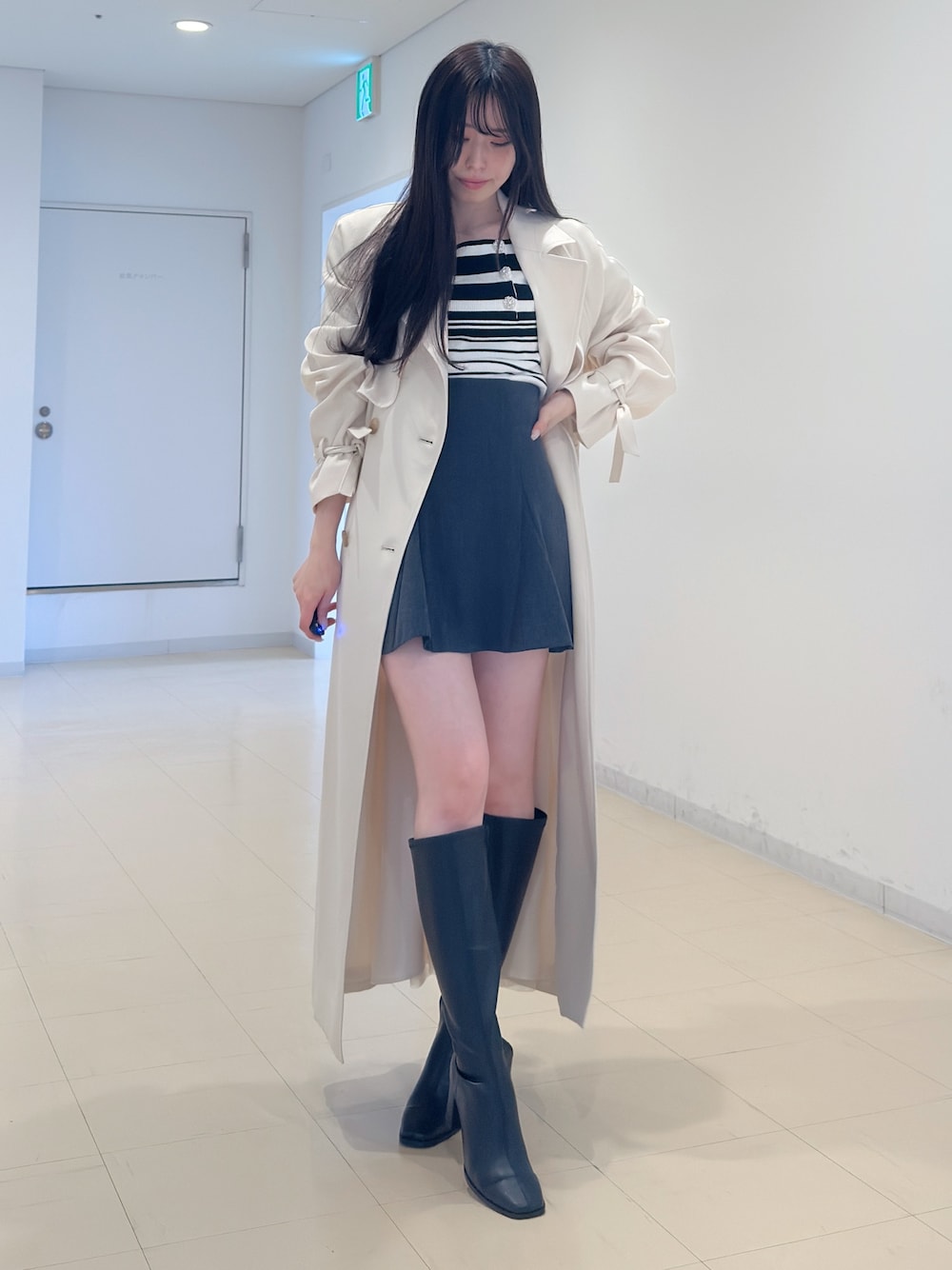 ホワイト系のトレンチコート、その他のニット/セーター、グレー系のスカートを着用したレディースの冬コーディネートの1枚目の写真