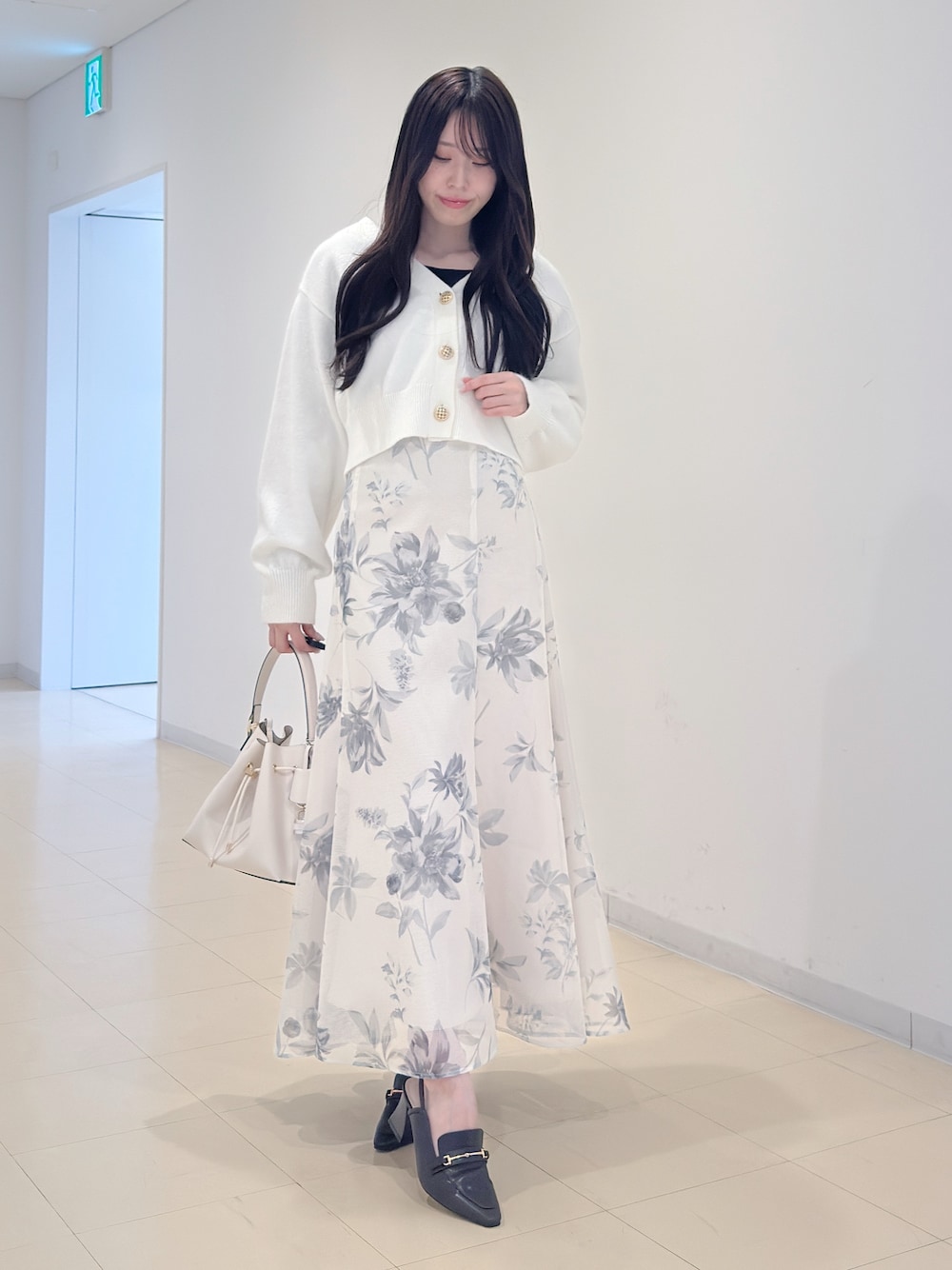 ホワイト系のカーディガン/ボレロ、ホワイト系のスカート、ホワイト系のショルダーバッグを着用したレディースの冬コーディネートの1枚目の写真