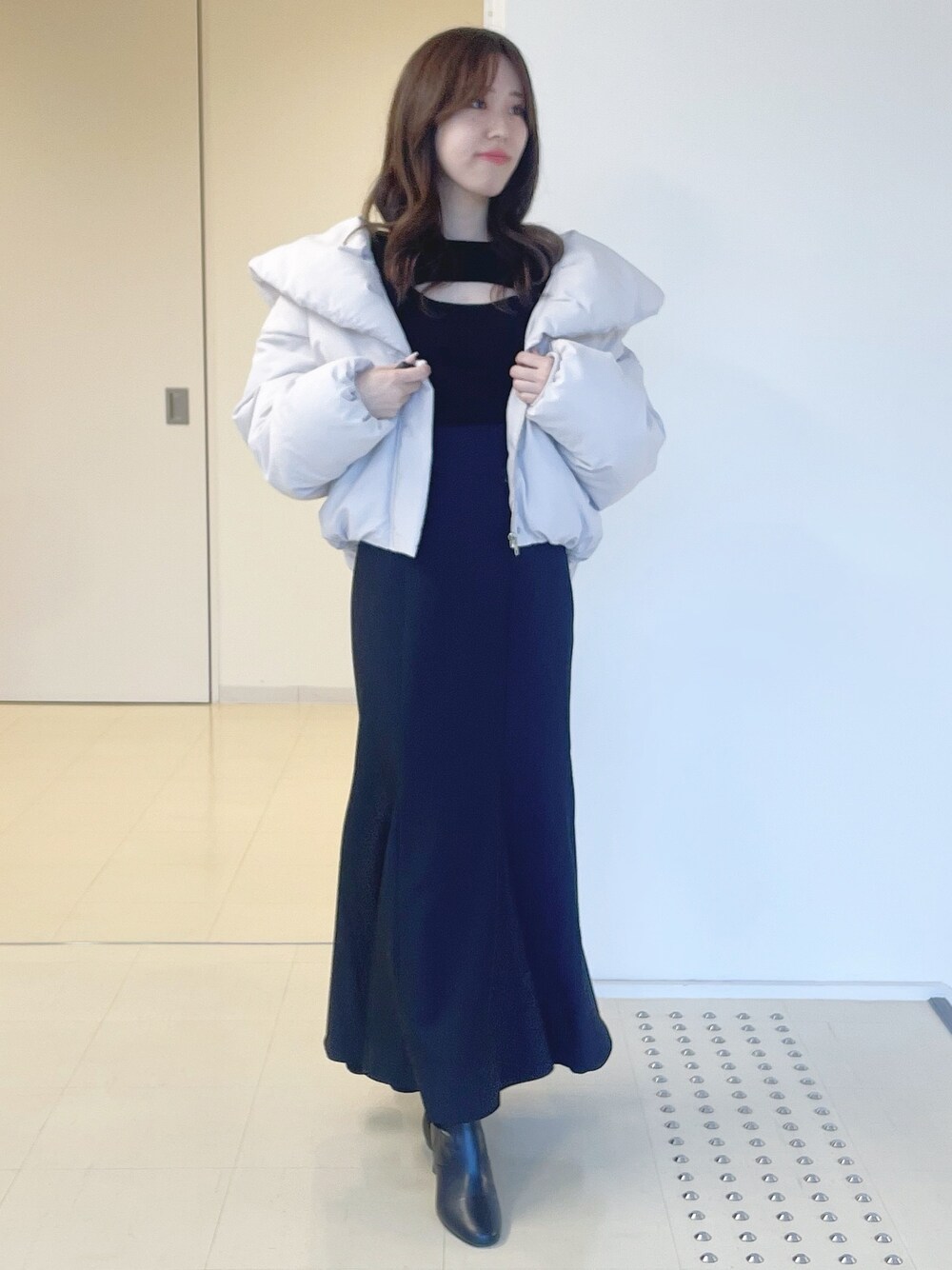 ブラック系のニット/セーター、ピンク系のダウンジャケット/コート、ブラック系のスカートを着用したレディースの冬コーディネートの1枚目の写真