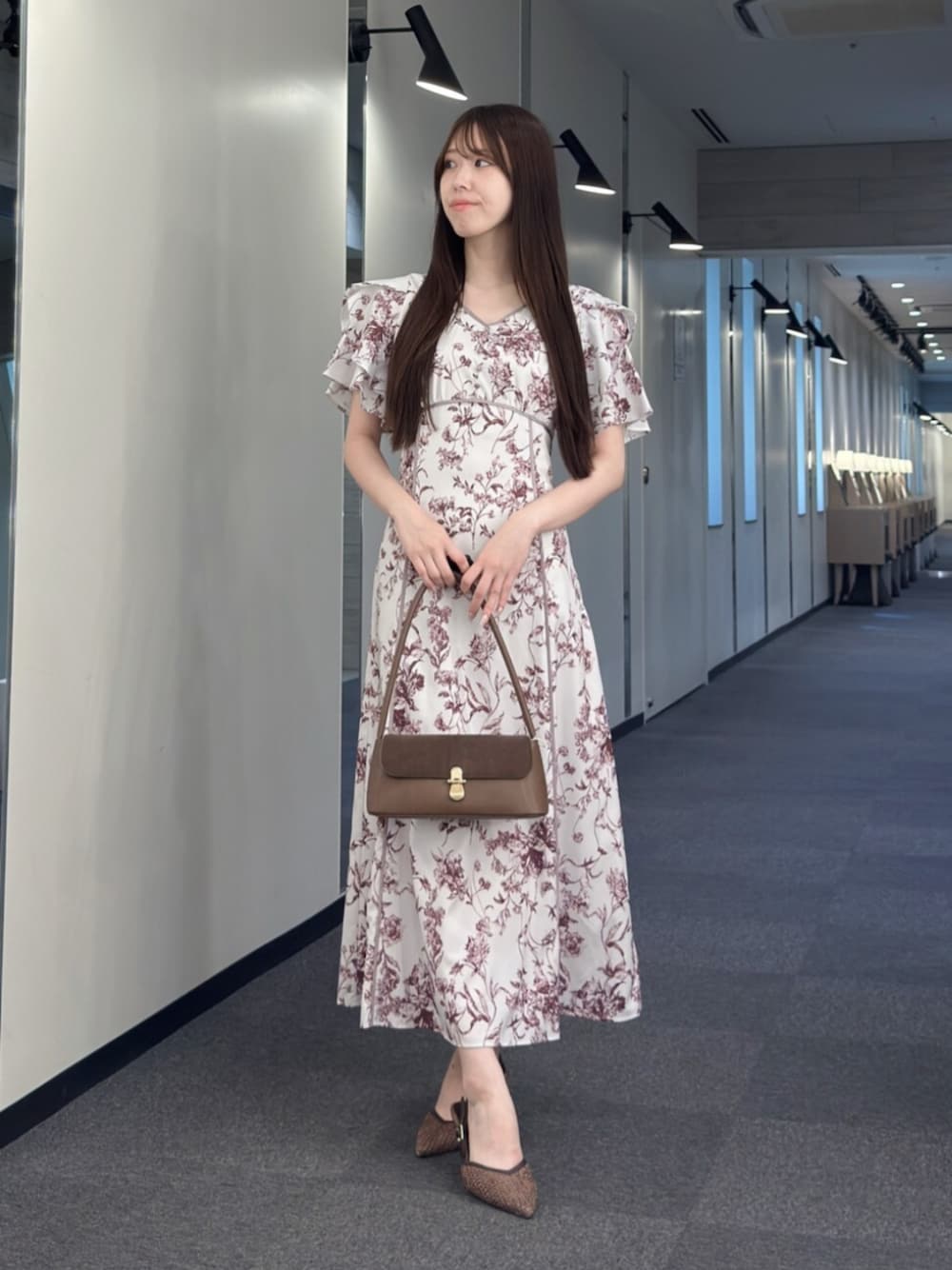 ブラウン系のハンドバッグ、ブラウン系のパンプス、レッド系のワンピースを着用したレディースの夏コーディネートの1枚目の写真