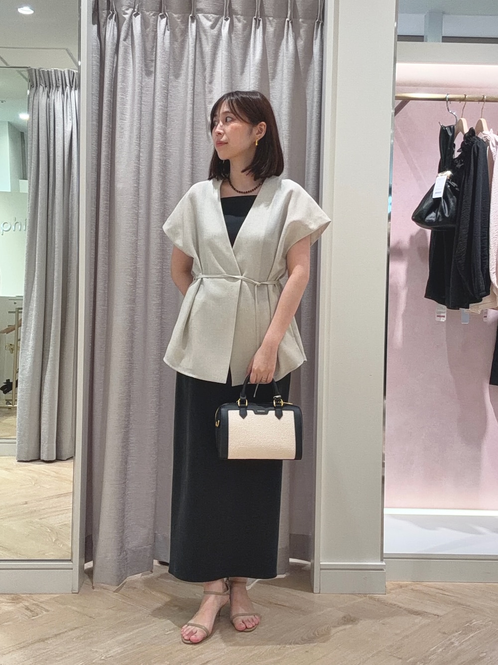 ベージュ系のベスト、ブラック系のスカート、ブラック系のボストンバッグを着用したレディースの夏コーディネートの1枚目の写真