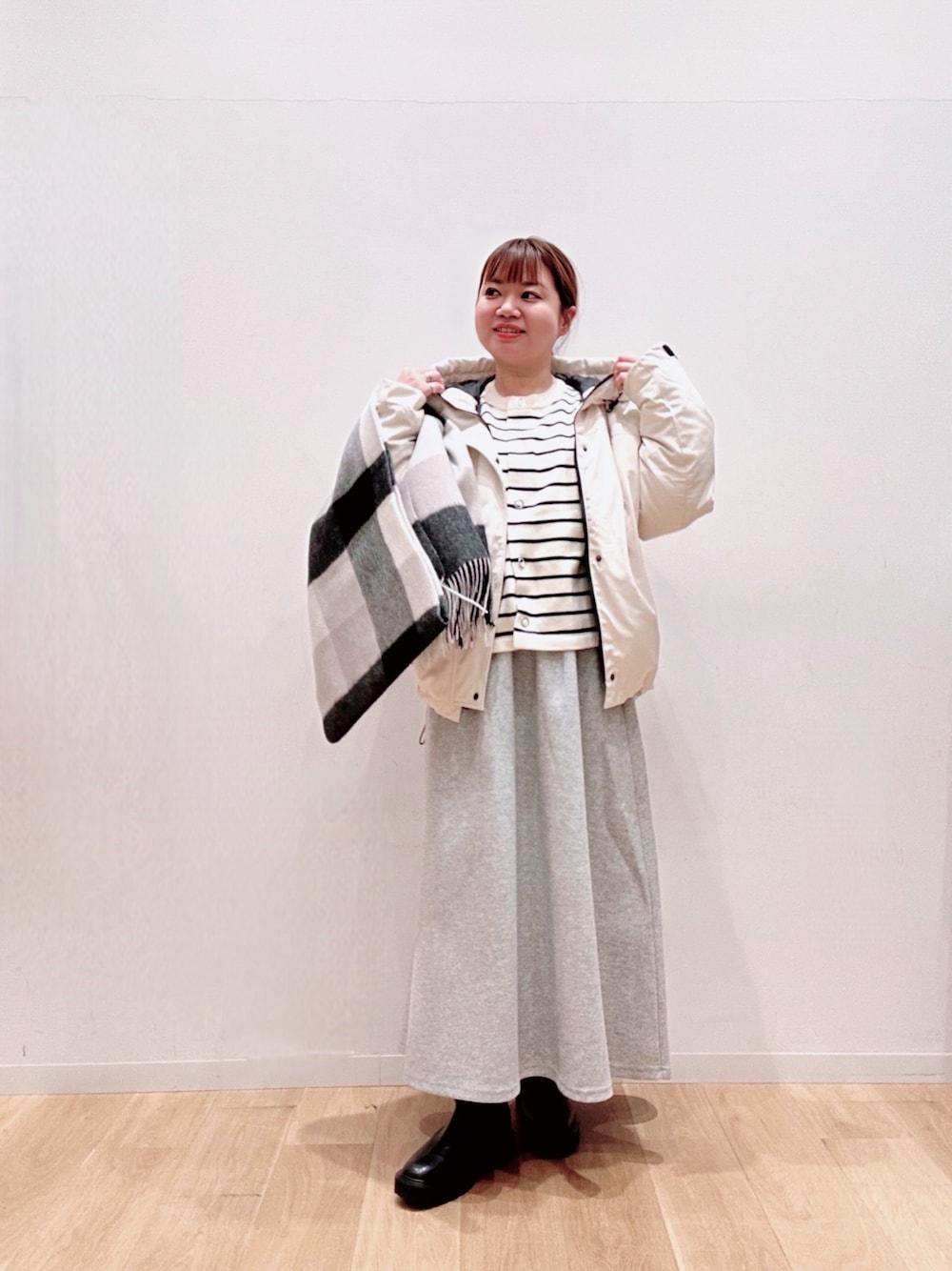 ホワイト系のカーディガン/ボレロ、ホワイト系のダウンジャケット/コート、グレー系のスカートを着用したレディースの秋コーディネートの1枚目の写真
