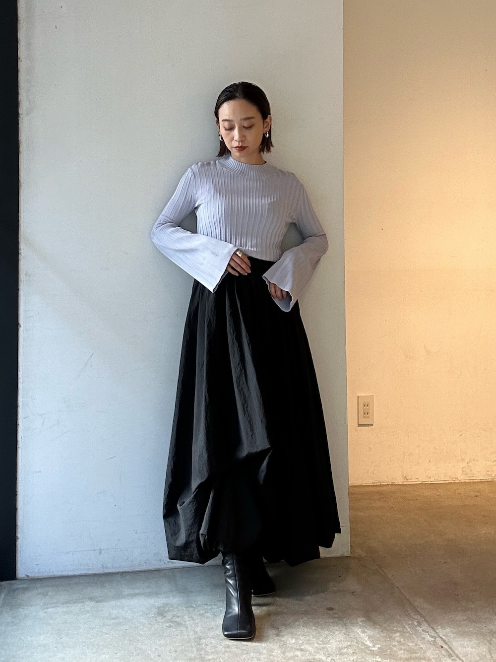 ブラック系のスカート、ブラック系のブーツ、パープル系のニット/セーターを着用したレディースの冬コーディネートの1枚目の写真