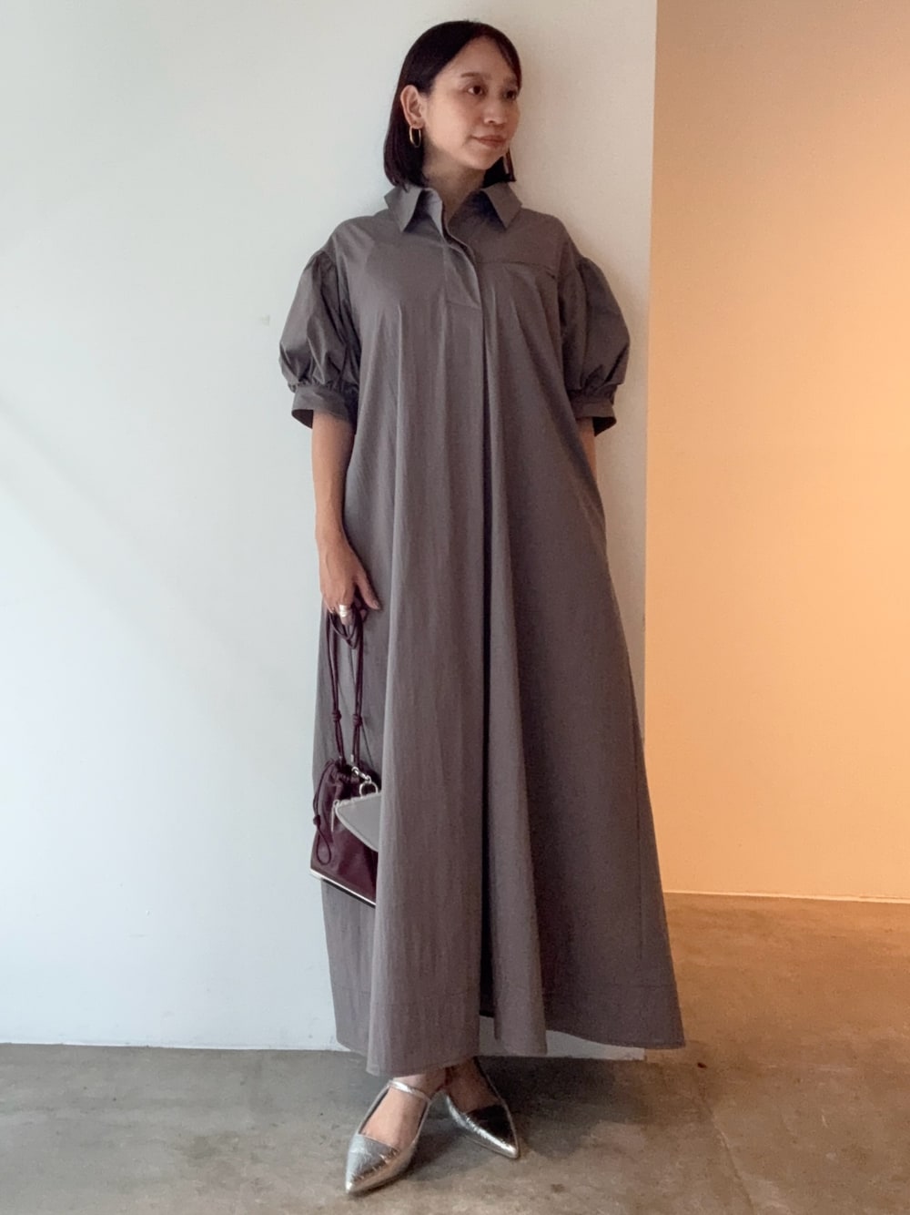 グレー系のワンピース、シルバー系のパンプス、レッド系のショルダーバッグを着用したレディースの夏コーディネートの1枚目の写真