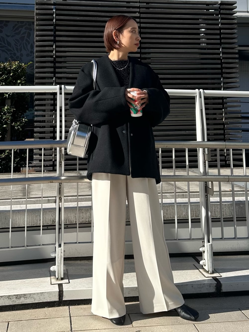 ブラック系のノーカラージャケット、シルバー系のボストンバッグ、ホワイト系のその他パンツを着用したレディースの冬コーディネートの1枚目の写真