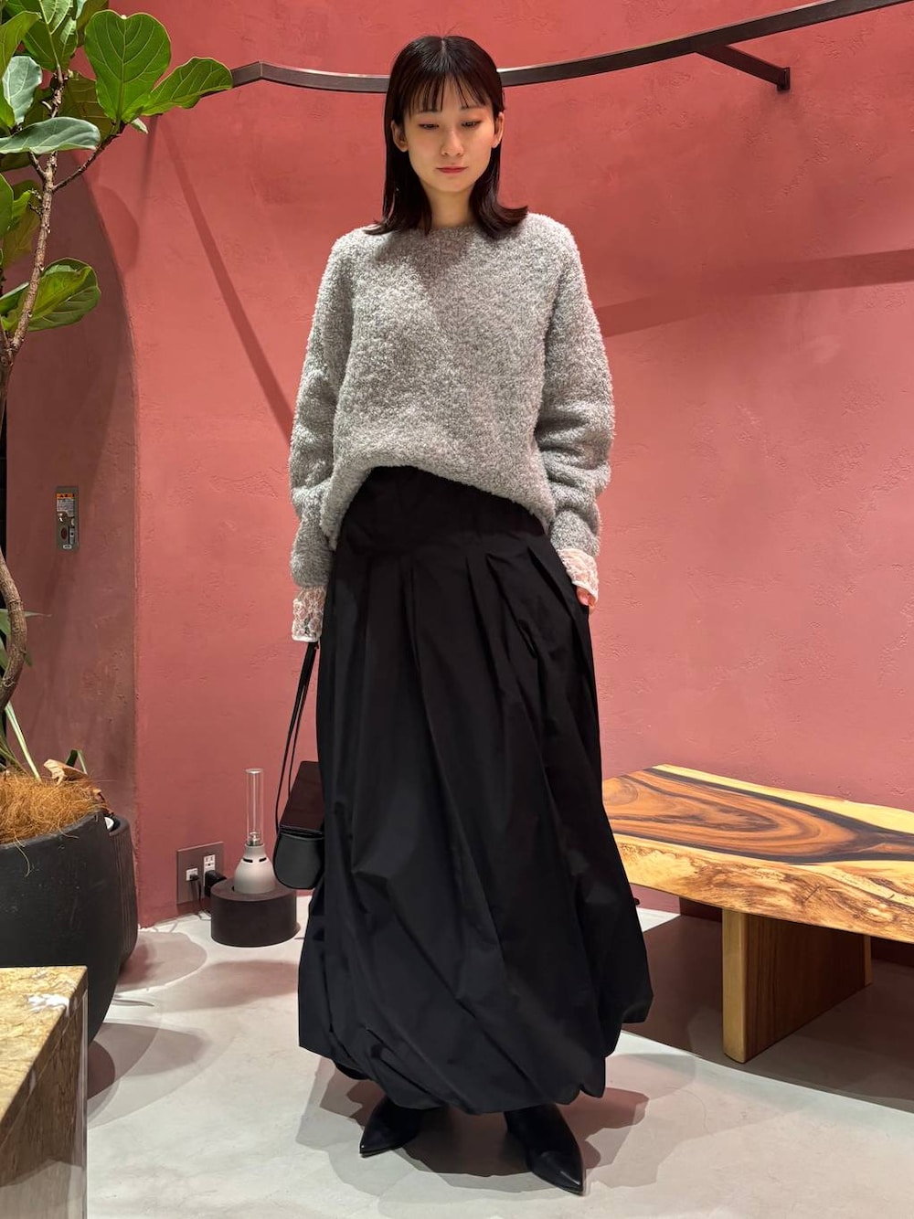 グレー系のニット/セーター、ホワイト系のTシャツ/カットソー、ブラック系のチェスターコートを着用したレディースの秋コーディネートの1枚目の写真