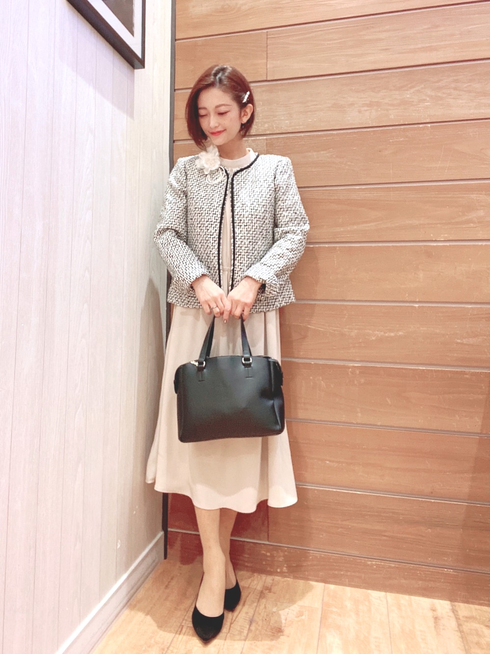 ブラック系のノーカラージャケット、ベージュ系のワンピース、ブラック系のトートバッグを着用したレディースの冬コーディネートの1枚目の写真