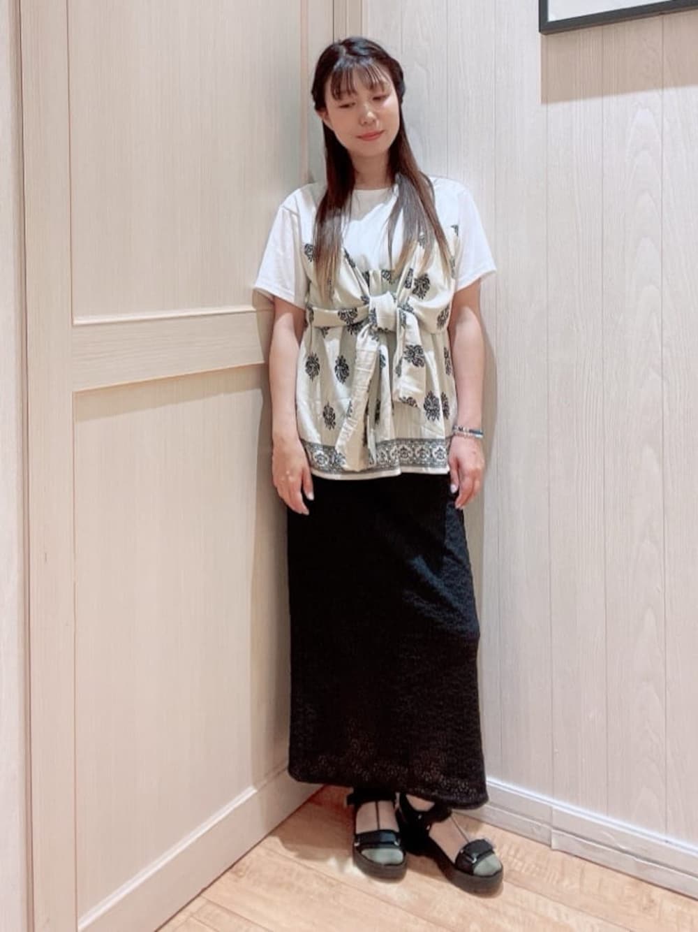 ベージュ系のTシャツ/カットソー、ブラック系のスカート、ブラック系のサンダルを着用したレディースの夏コーディネートの1枚目の写真