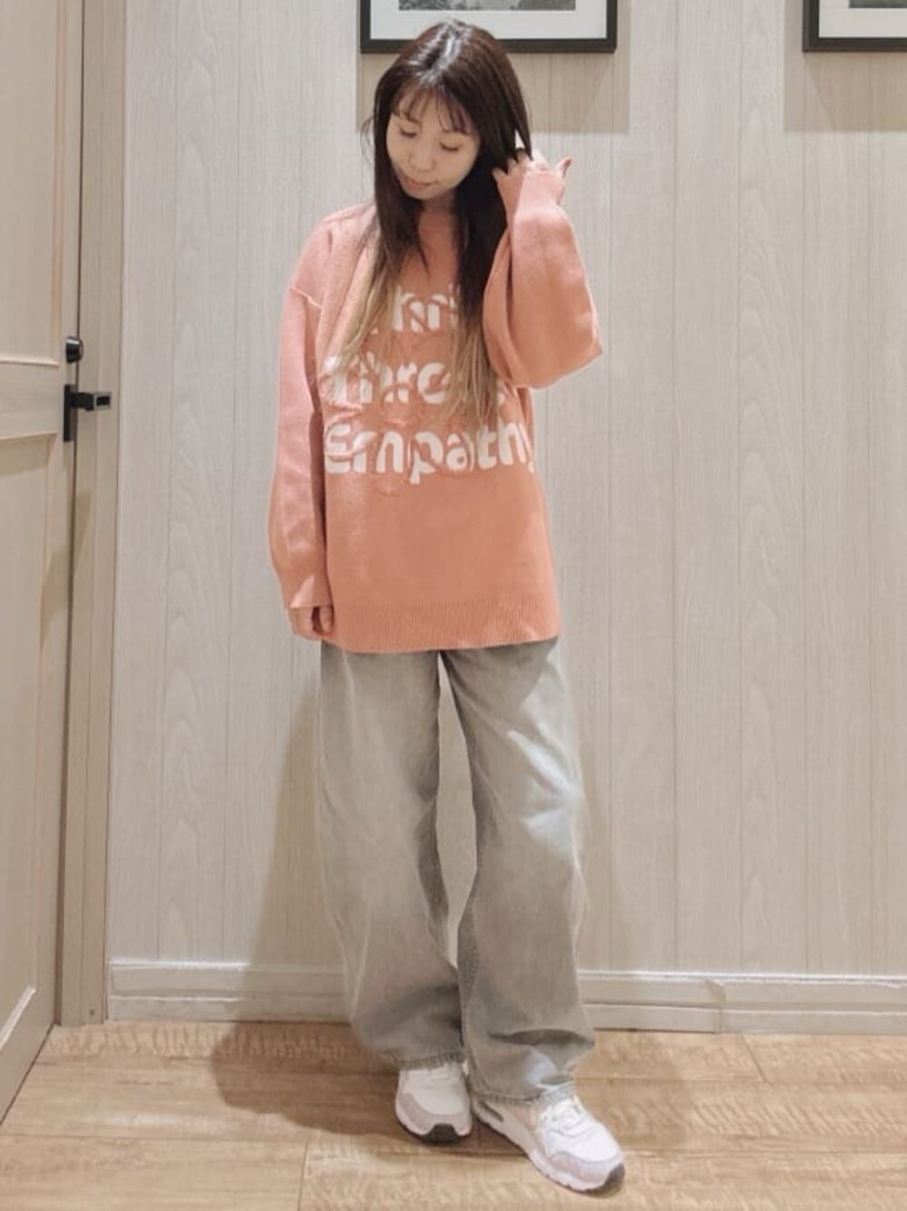 オレンジ系のニット/セーター、グレー系のデニムパンツを着用したレディースの冬コーディネートの1枚目の写真