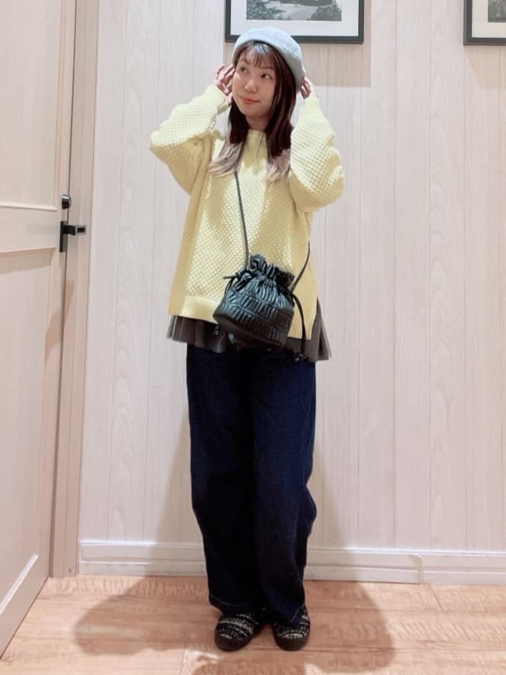 イエロー系のニット/セーター、グレー系のTシャツ/カットソー、ブラック系のショルダーバッグを着用したレディースの冬コーディネートの1枚目の写真