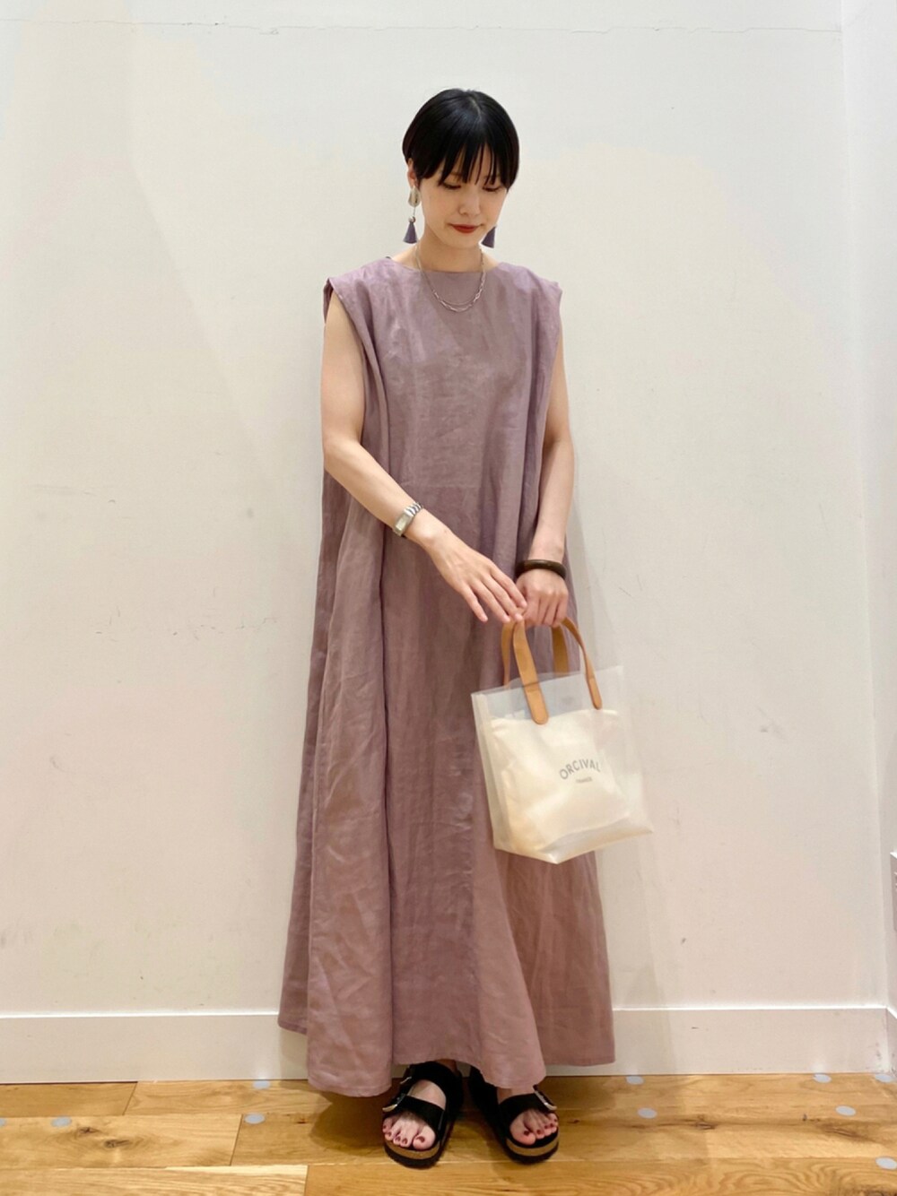 パープル系のワンピース、ホワイト系のトートバッグ、ブラック系のサンダルを着用したレディースの夏コーディネートの1枚目の写真