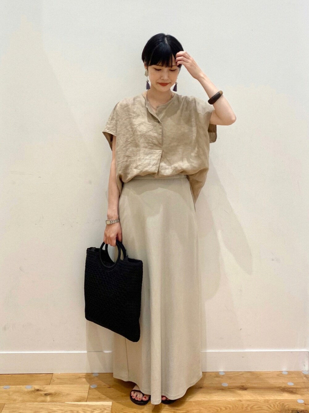 ベージュ系のTシャツ/カットソー、グレー系のスカート、ブラック系のトートバッグを着用したレディースの夏コーディネートの1枚目の写真