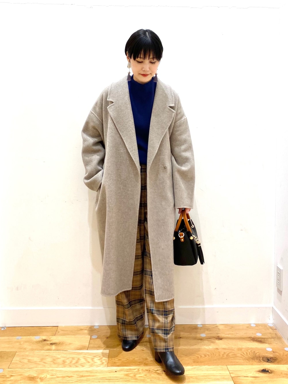 グレー系のチェスターコート、ブルー系のニット/セーター、ベージュ系のその他パンツを着用したレディースの秋コーディネートの1枚目の写真