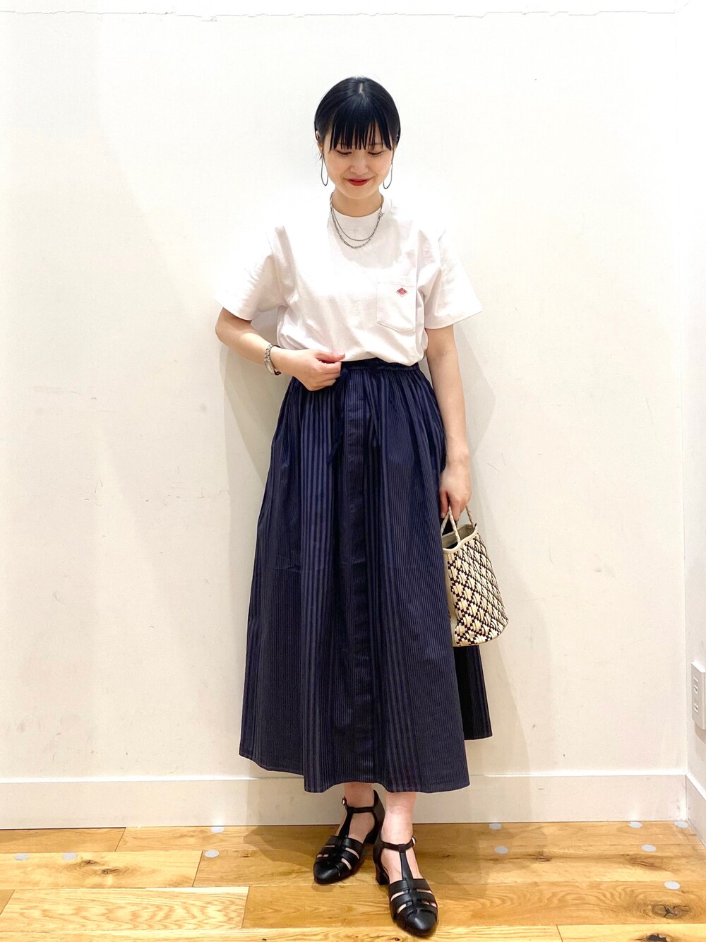 グレー系のスカート、ブラック系のサンダル、ホワイト系のその他を着用したレディースの春コーディネートの1枚目の写真