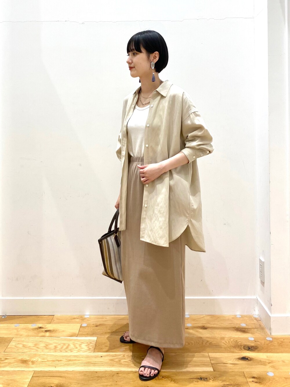 ベージュ系のシャツ/ブラウス、ホワイト系のタンクトップ、ベージュ系のスカートを着用したレディースの春コーディネートの1枚目の写真