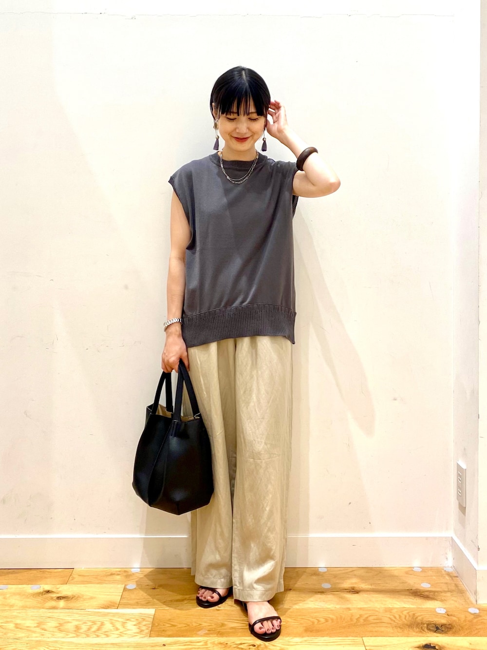 グレー系のニット/セーター、ベージュ系のその他パンツ、ブラック系のトートバッグを着用したレディースの夏コーディネートの1枚目の写真