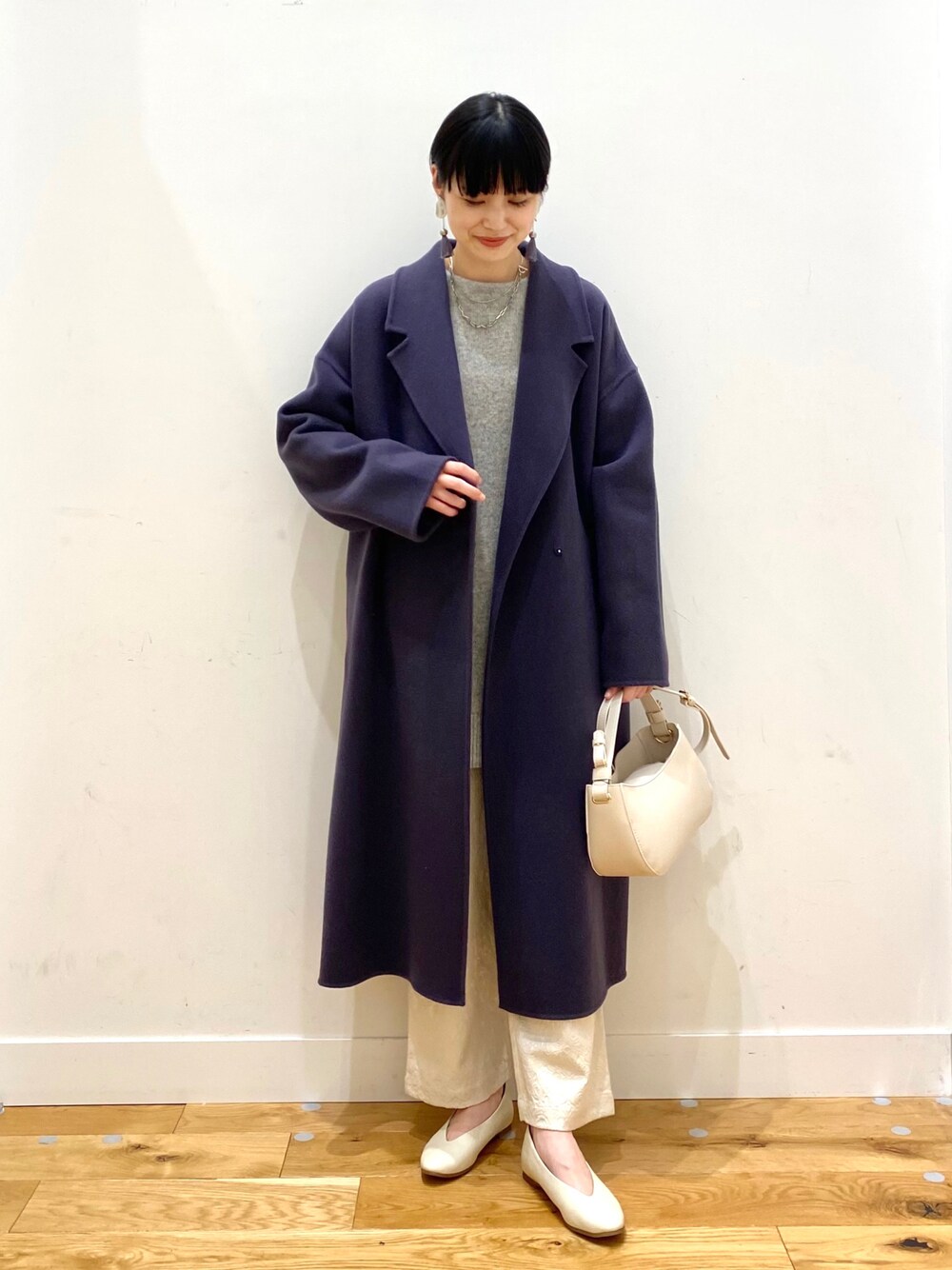 ブルー系のチェスターコート、グレー系のニット/セーター、ホワイト系のその他パンツを着用したレディースの冬コーディネートの1枚目の写真