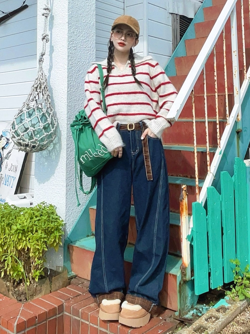 ブルー系のデニムパンツ、グリーン系のバックパック/リュック、ベージュ系のブーツを着用したレディースの秋コーディネートの1枚目の写真