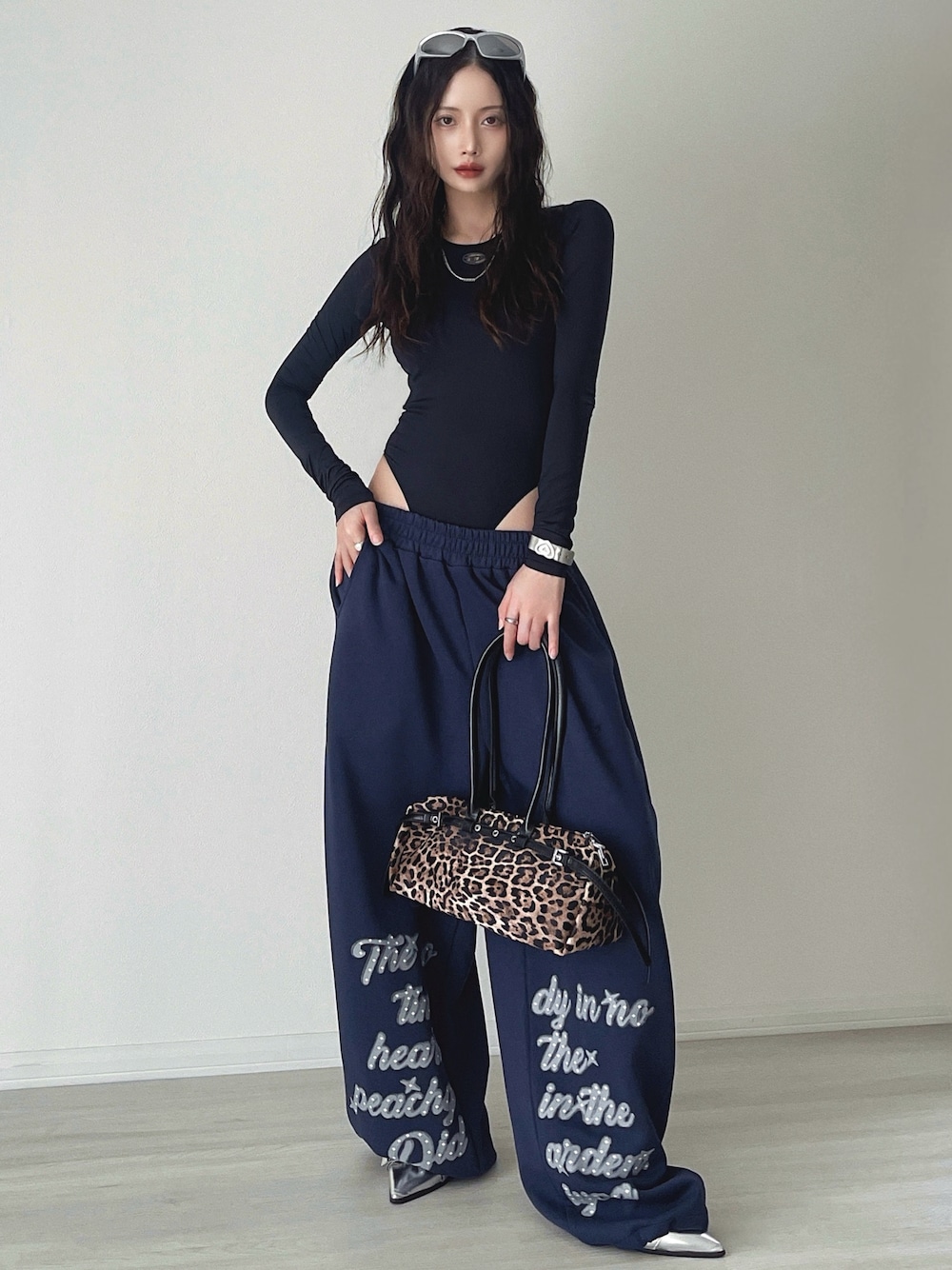 シルバー系のサンダル、ブルー系のスウェットパンツ、ブラウン系のショルダーバッグを着用したレディースの秋コーディネートの1枚目の写真